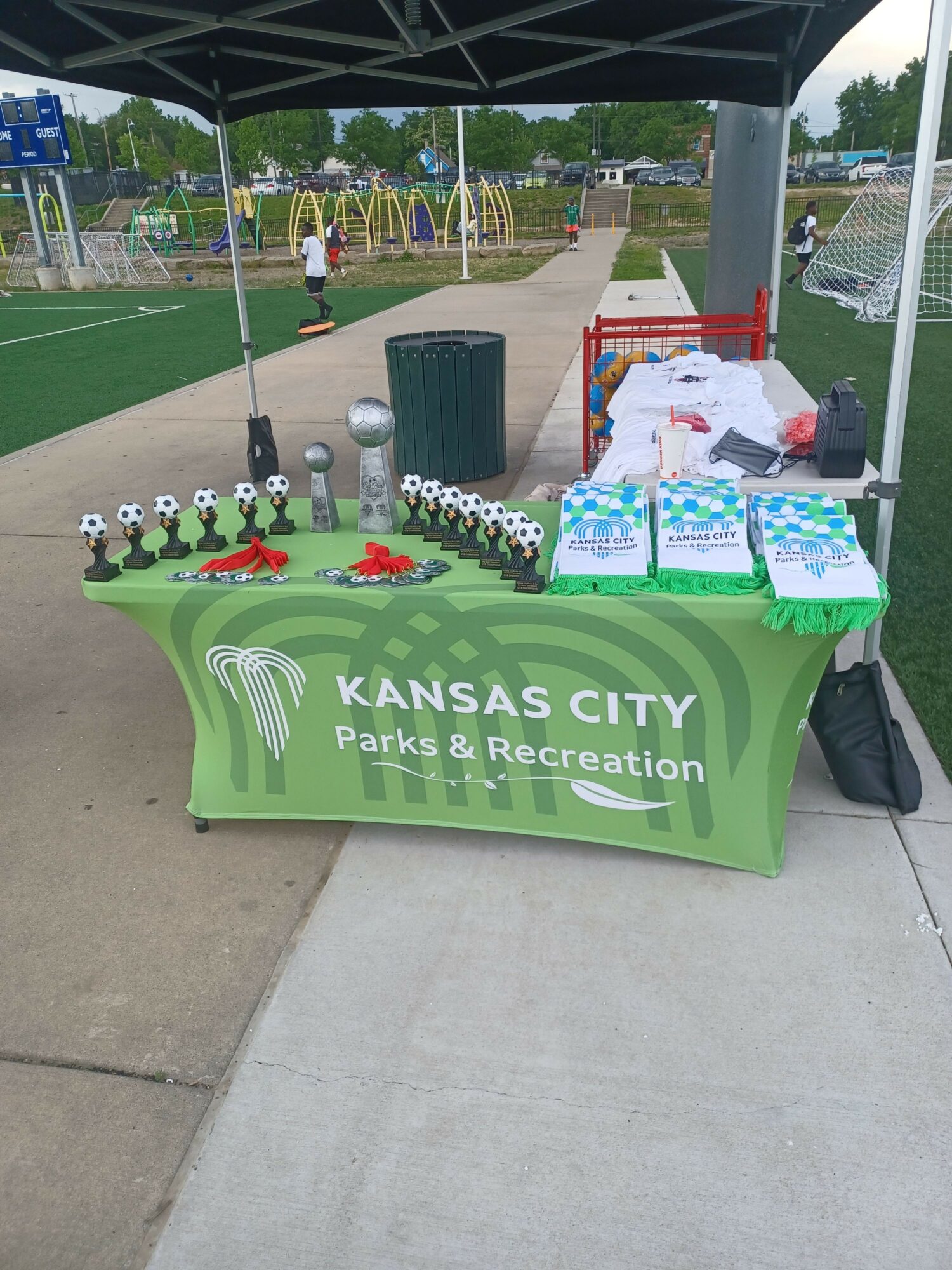 Kansas City Parks and Recreation table with brochures and small trophies on a sidewalk.
