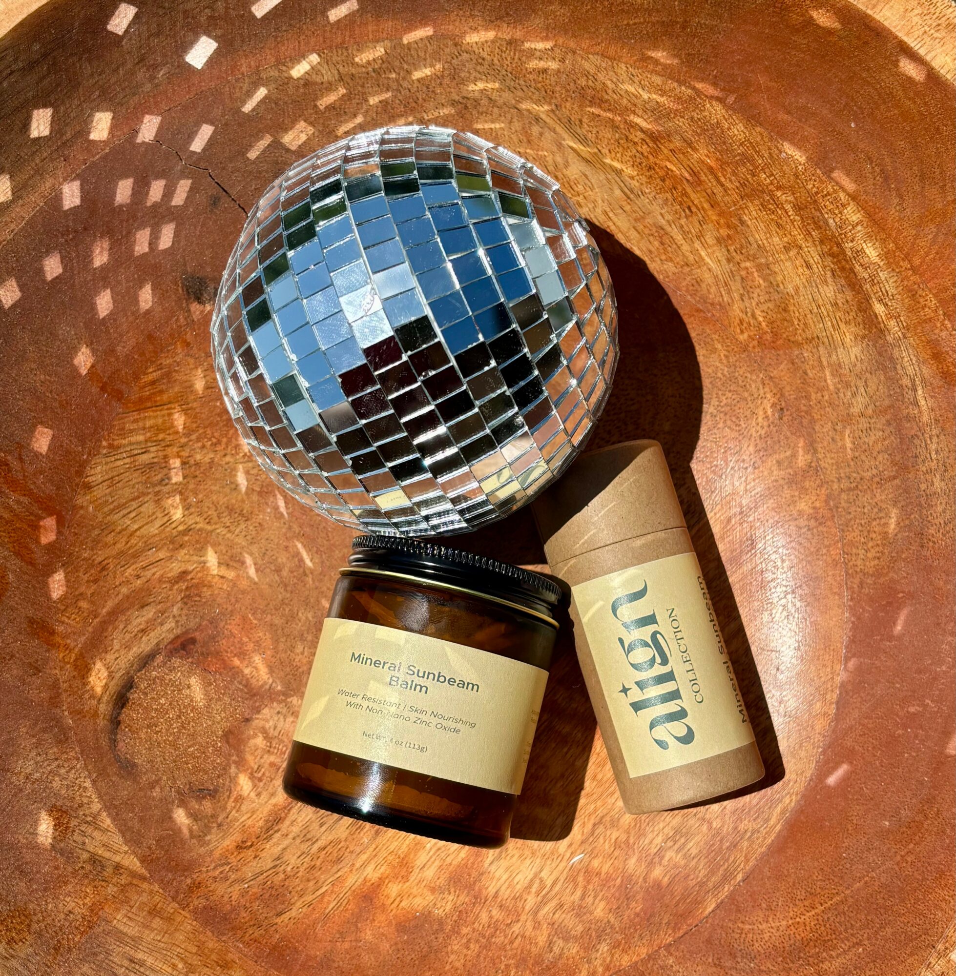 A disco ball, a jar labeled 'Mineral Sunscreen,' and a tube labeled 'Aesop' inside a copper bowl.