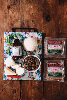 Food items including a jar, cheese, a bowl of ground meat, and two packages on a wooden surface.