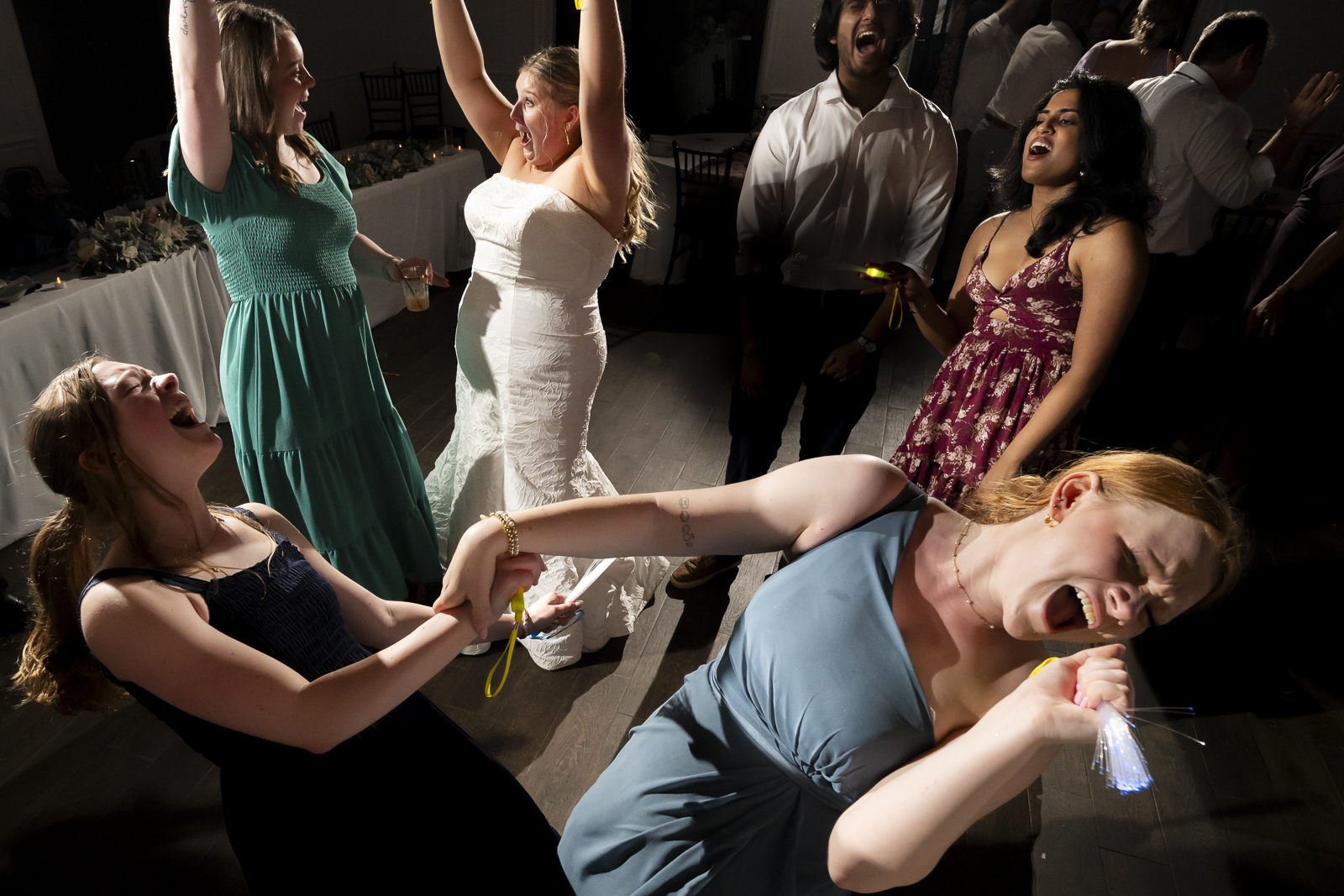 Group of people dancing and socializing at a party, some holding drinks, with a cityscape in the background.