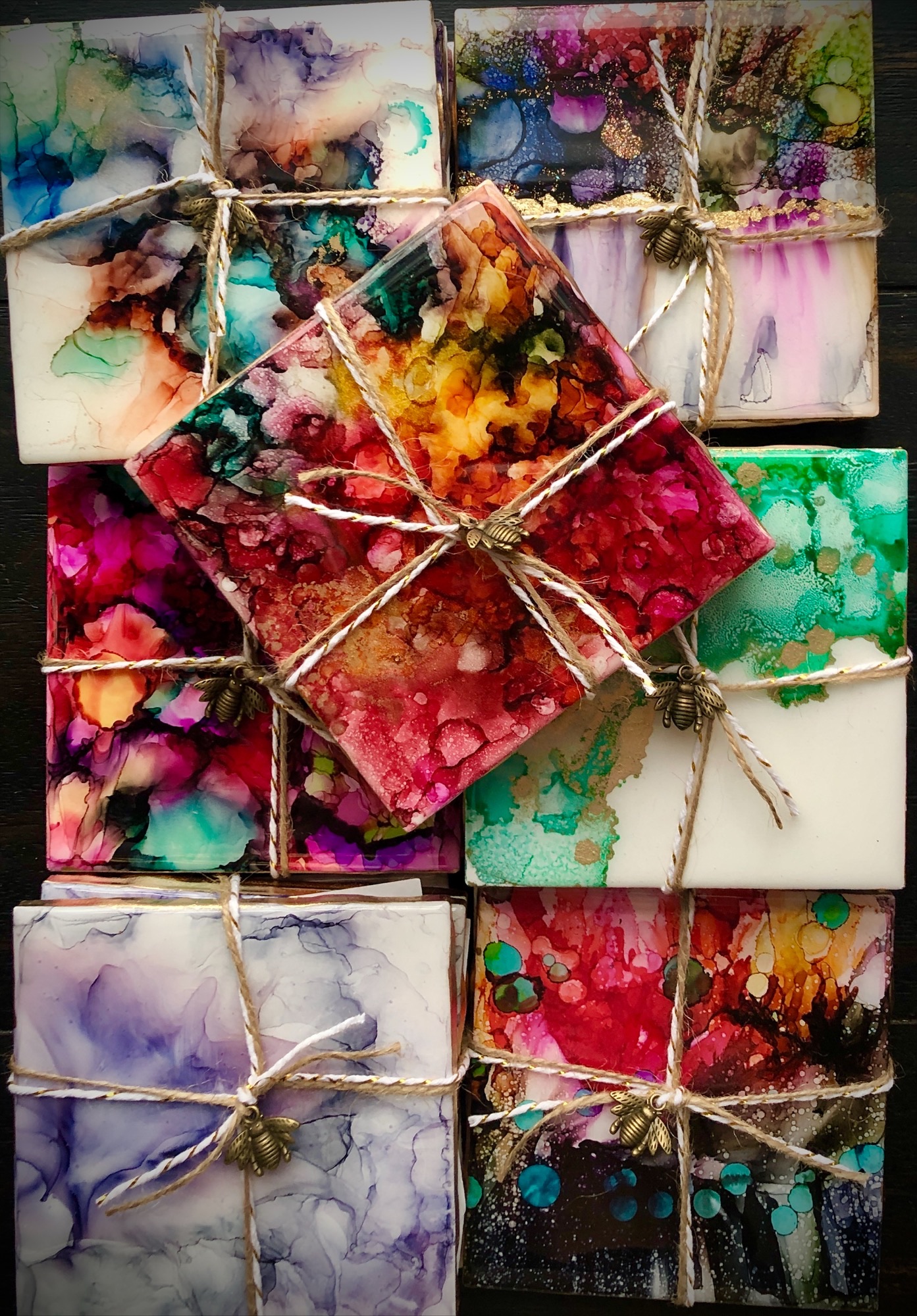 Colorful abstract paintings tied with twine, arranged in a grid pattern, with various vibrant colors and textures.