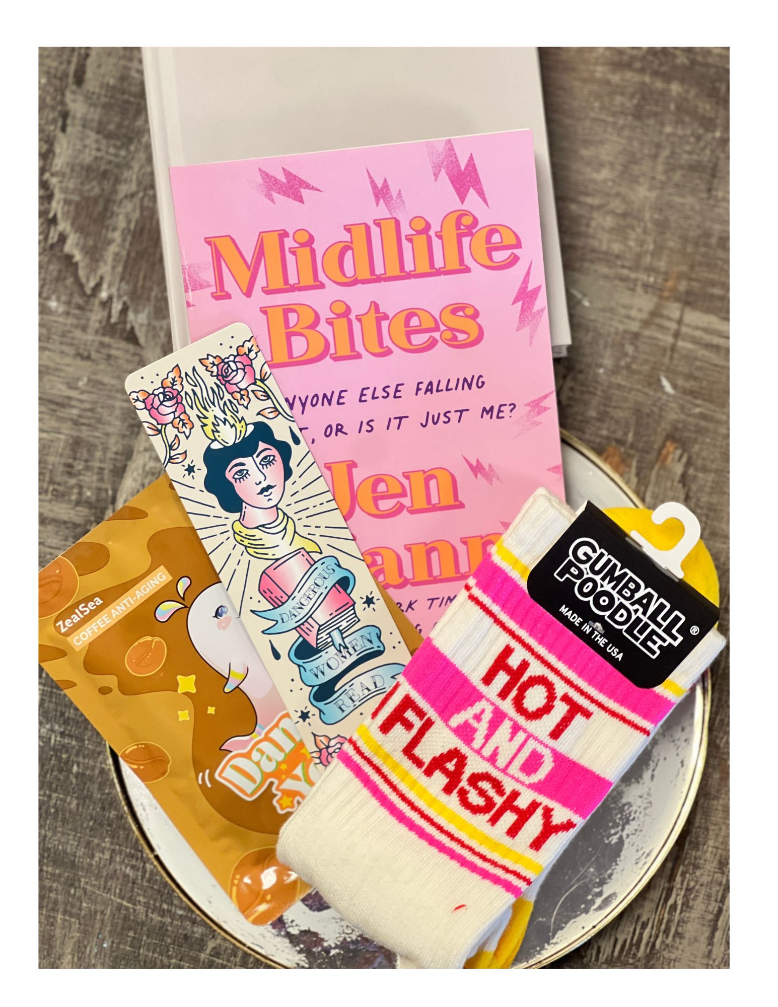 A tray with a pink book titled 'Millie Bites', a colorful illustrated card, a pair of socks with pink and yellow stripes, and a small plush toy.