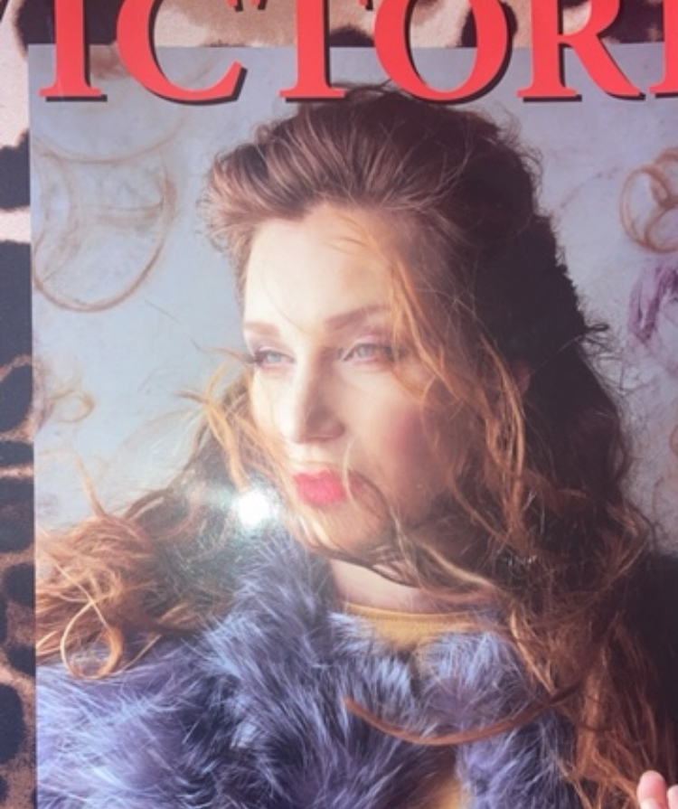 Magazine cover featuring a woman with long, curly hair looking to the side, wearing a blue fur coat.