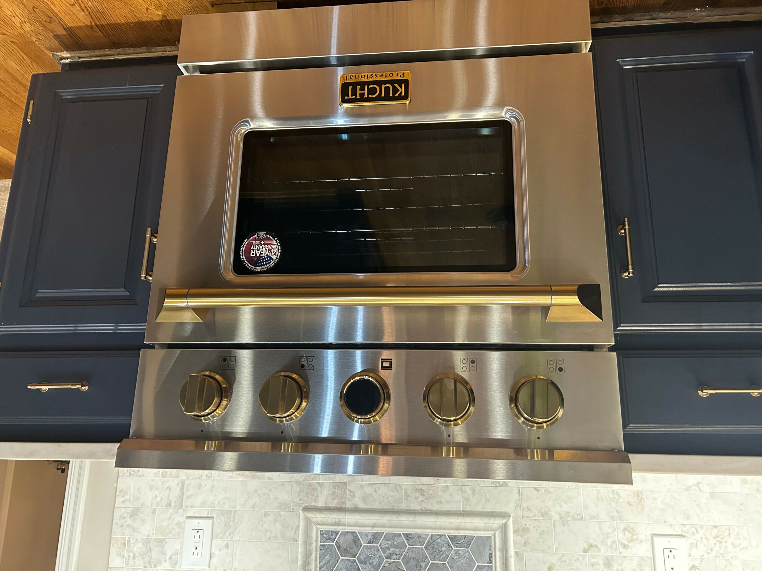 Stainless steel oven with control knobs, flanked by dark cabinets, and a window in the oven door.