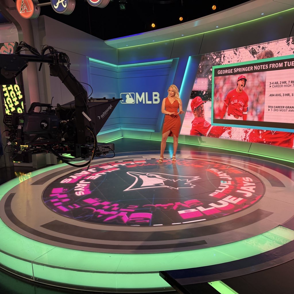 TV studio with a female presenter in a red dress, a large screen showing a hockey player, and a circular floor graphic.