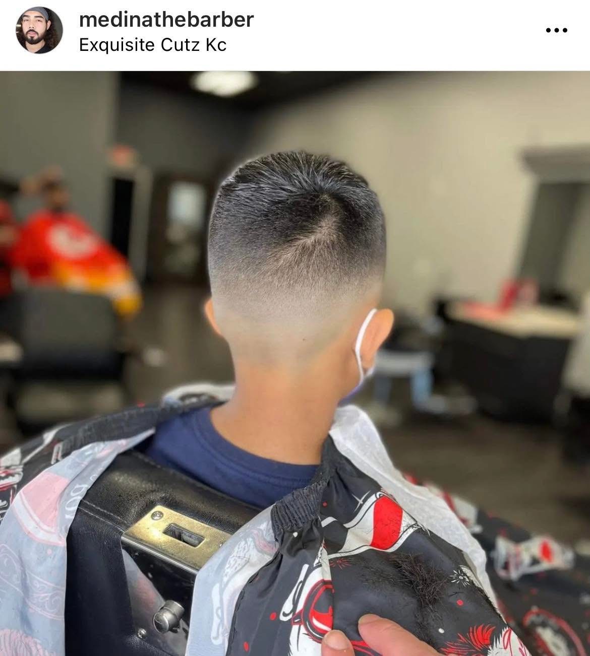 Back of a person's head with a short fade haircut, wearing a backpack and a face mask, indoors.