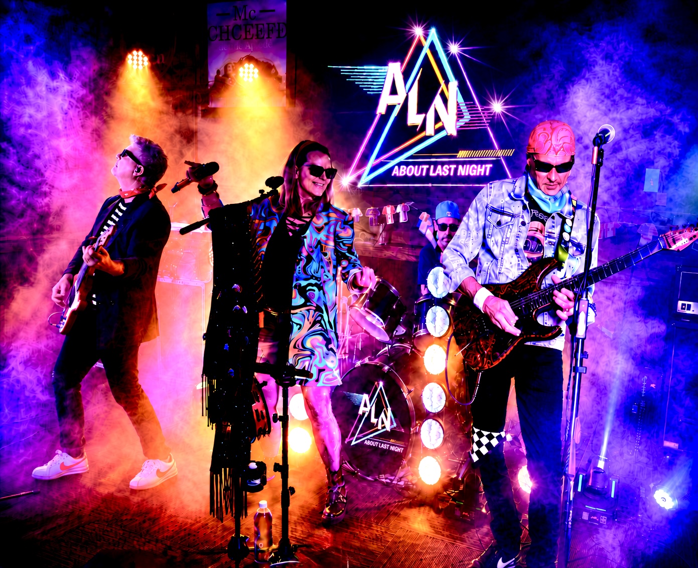 Band performing on stage with colorful lights and a neon sign reading 'ALMA' and 'About Last Night'.