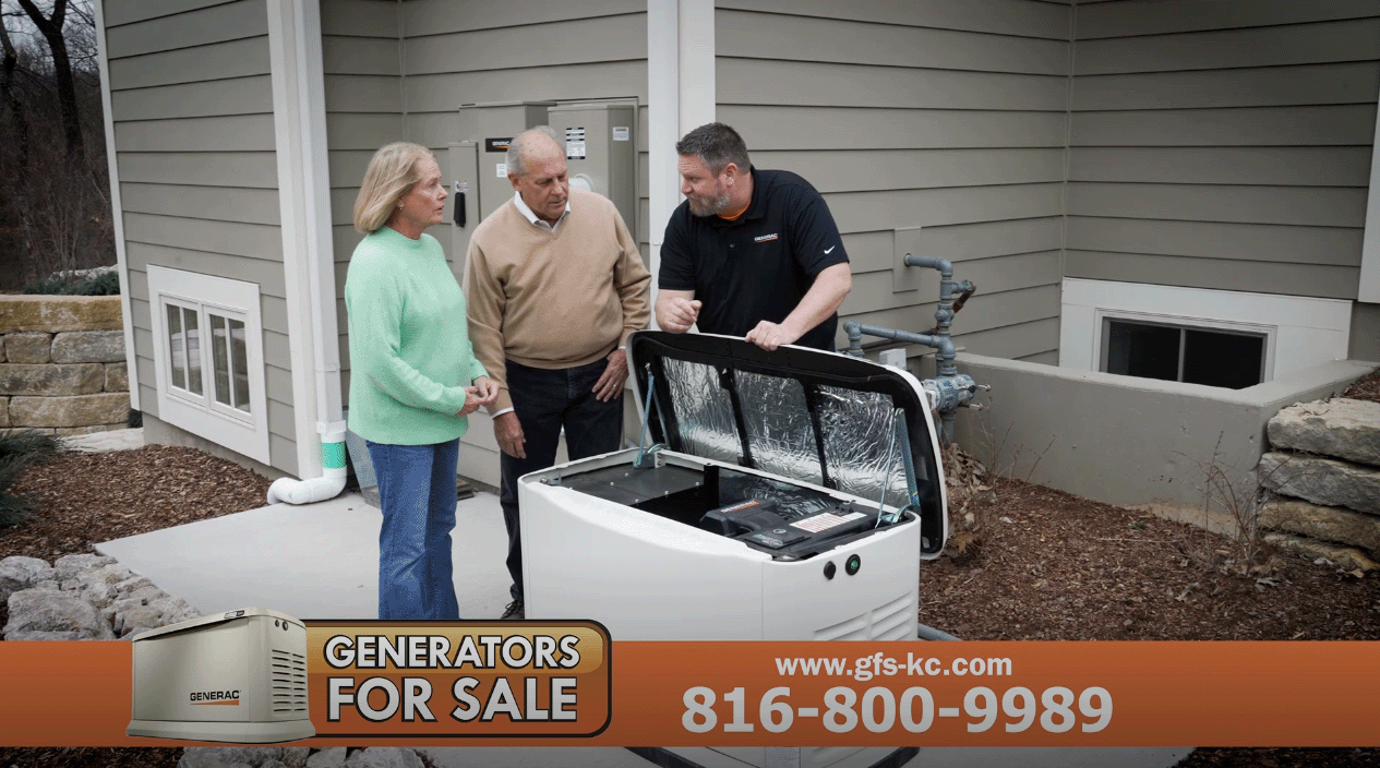 Three people stand outside near a large white freezer, with a man showing something to two women, in front of a house.