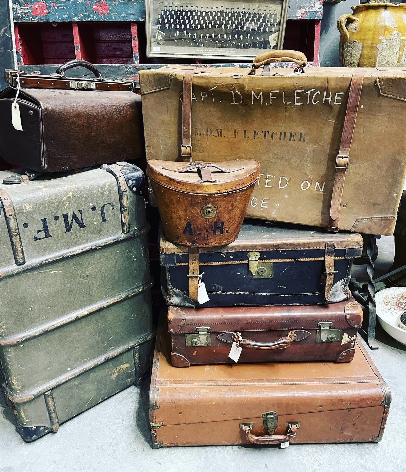 Stack of vintage suitcases and bags in various sizes and colors, some with handles and clasps, on a surface.