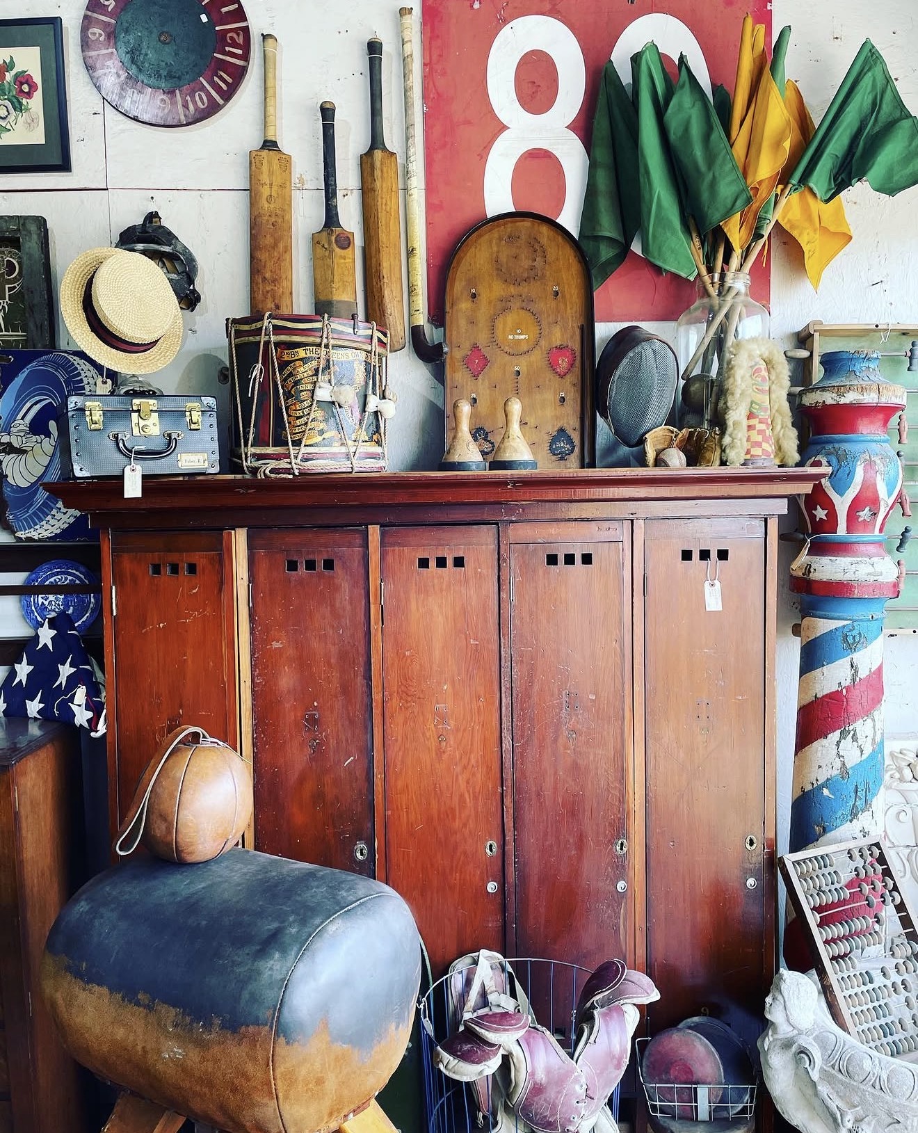 Wooden cabinet with various decorative items and sports memorabilia on top, including flags, a clock, and a vintage radio.
