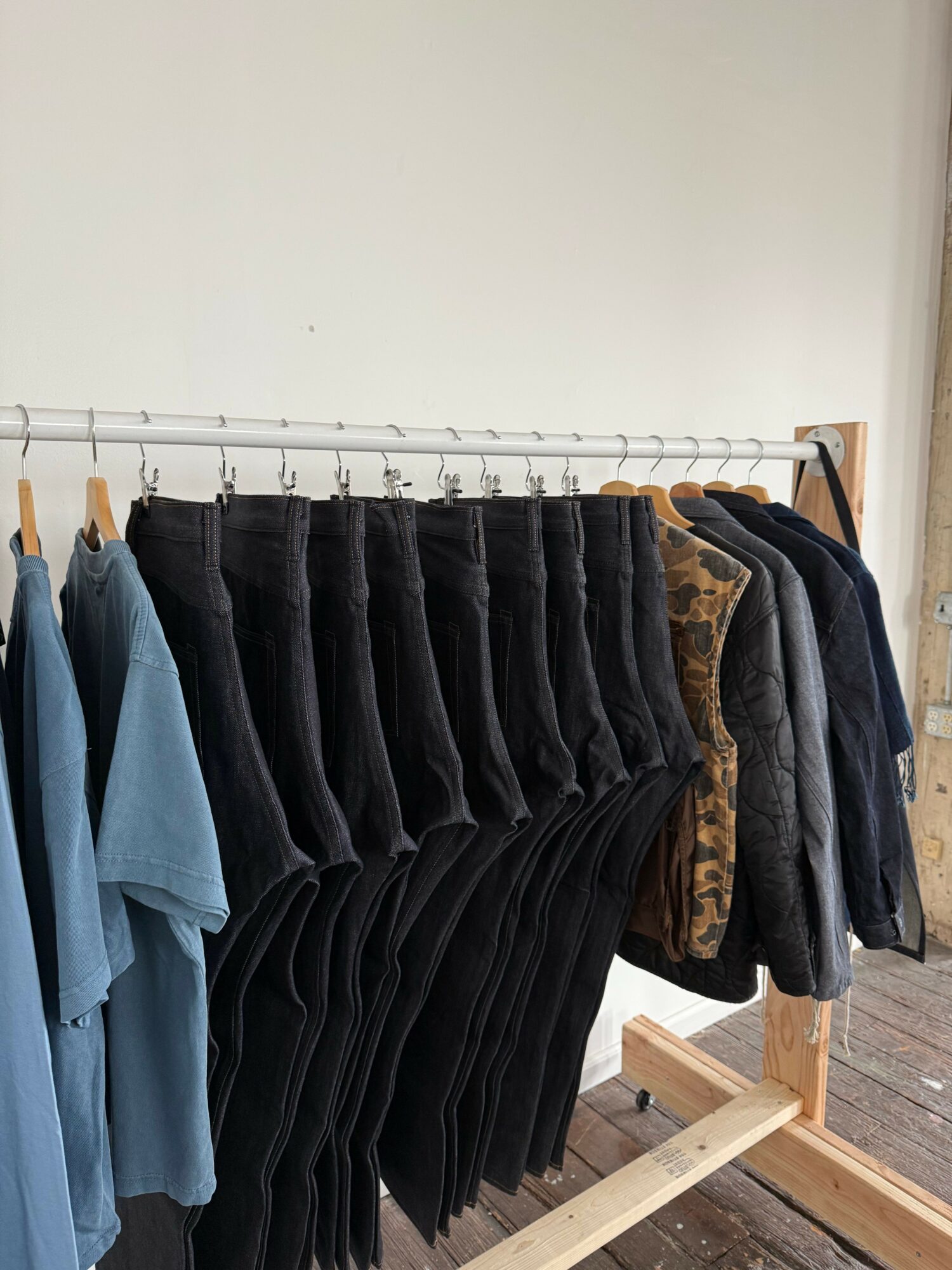 Stacked black and blue clothing items on a wooden surface, with a white wall in the background.