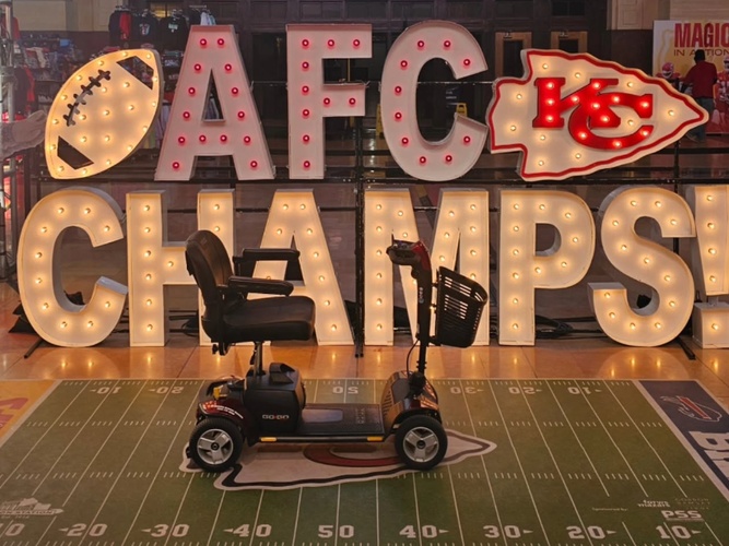Scooter on a football field with illuminated signs spelling 'AFC CHAMPS' in the background.
