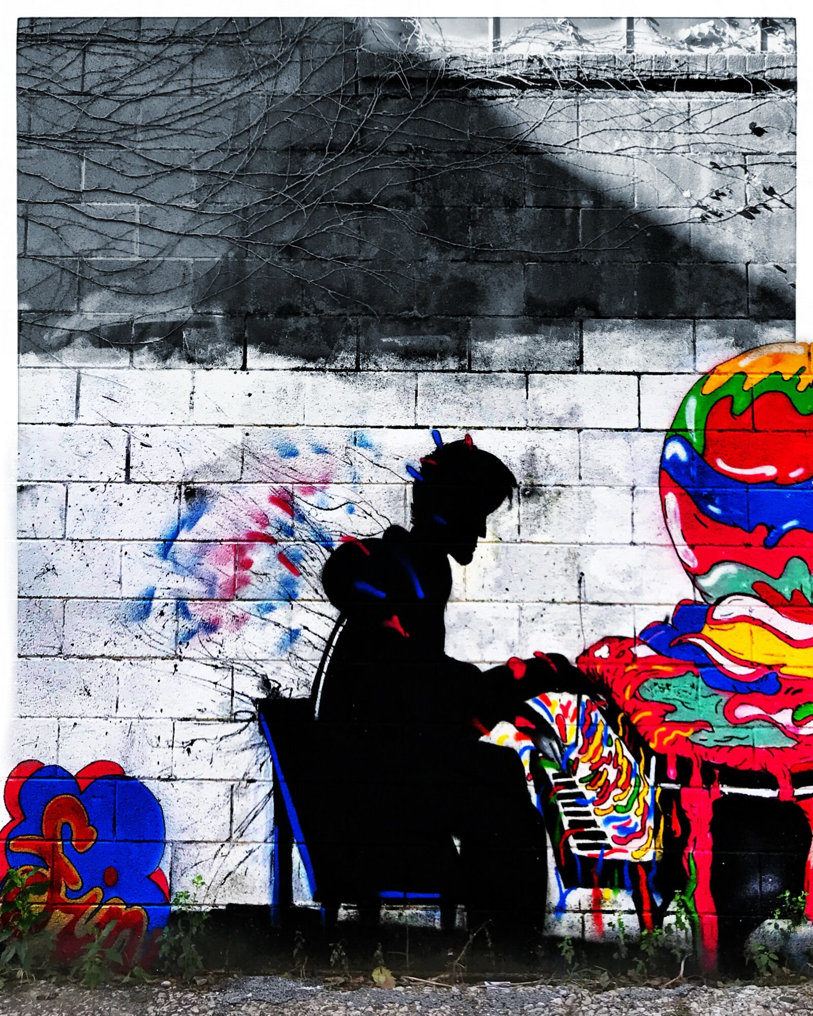 Silhouette of a person sitting on a chair in front of a graffiti-covered wall with colorful abstract art.