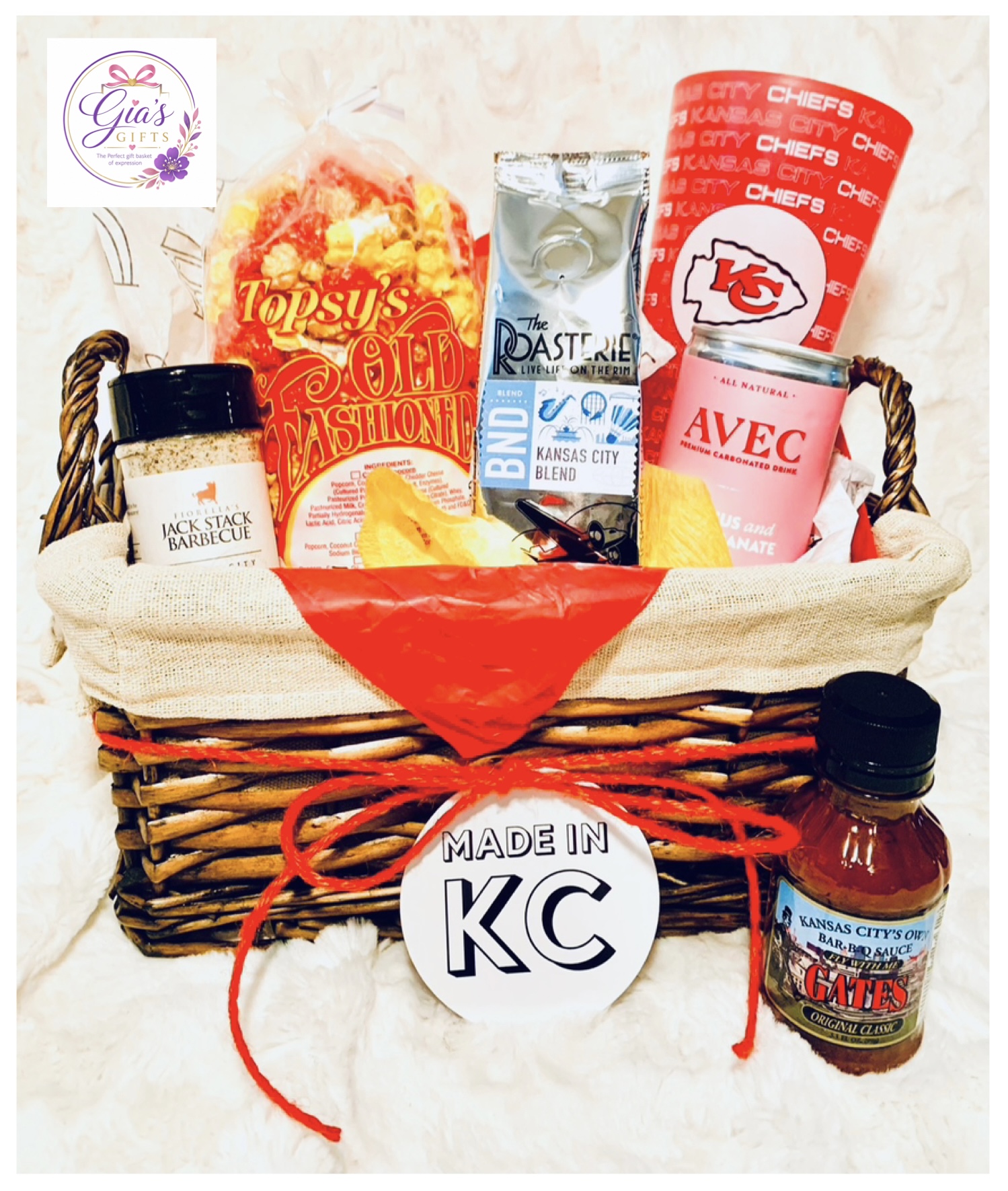 Basket with Kansas City-themed snacks and items, including popcorn, drink, and condiments, on a white surface.