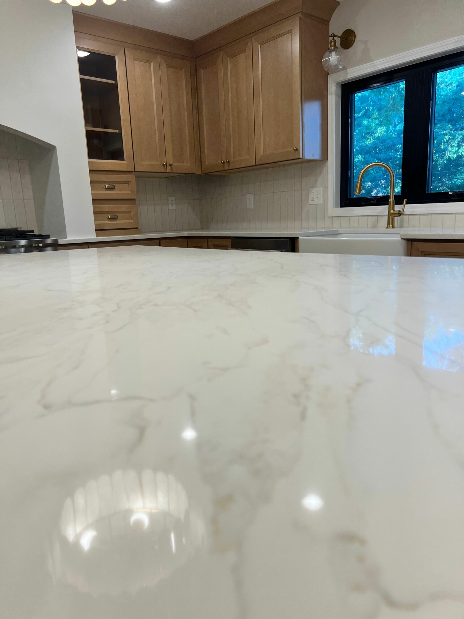 Kitchen with marble countertop, wooden cabinets, window, and a view outside, viewed from the side.
