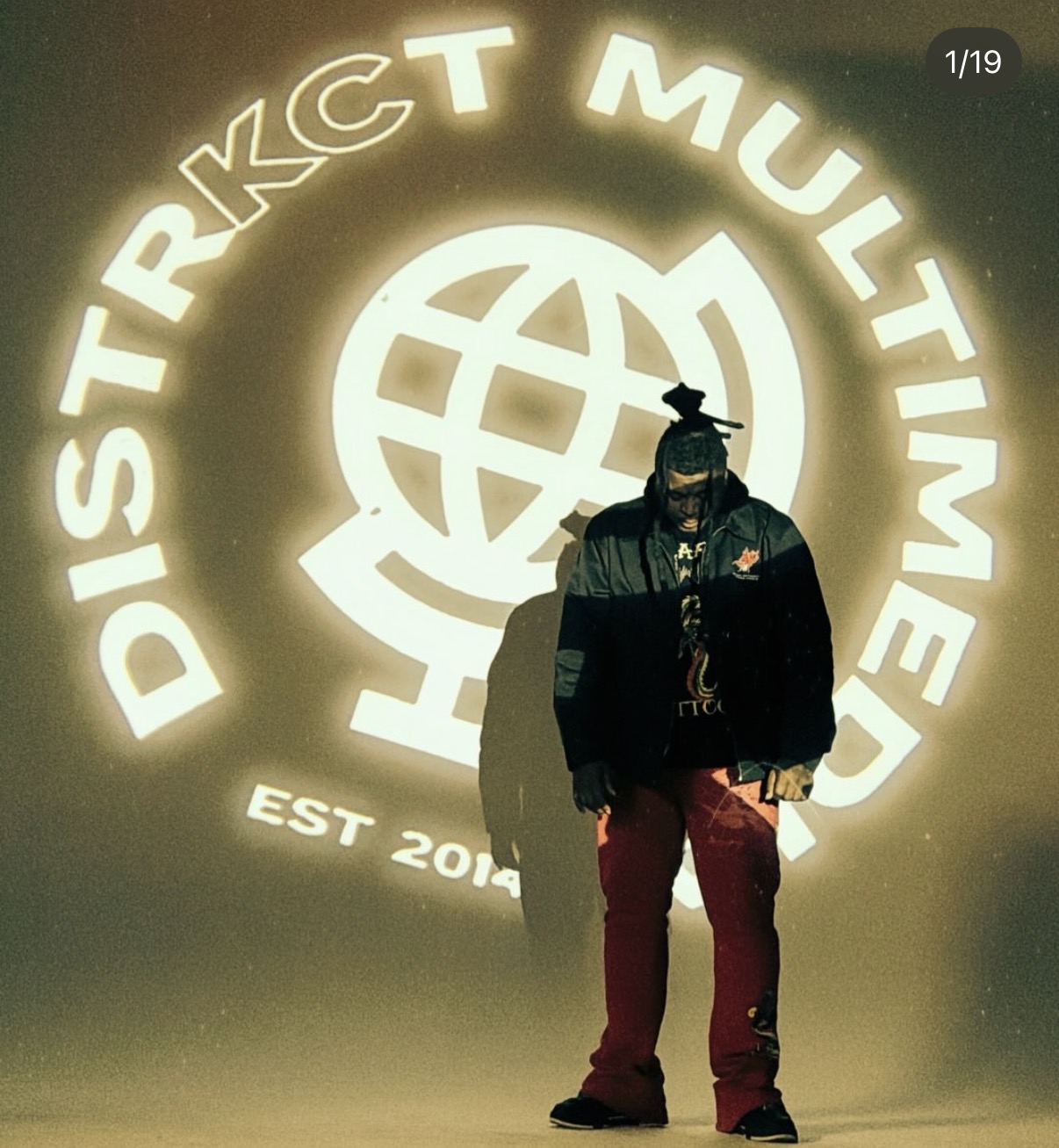 Person standing in front of a glowing logo with text and a globe symbol, casting a shadow on the wall.