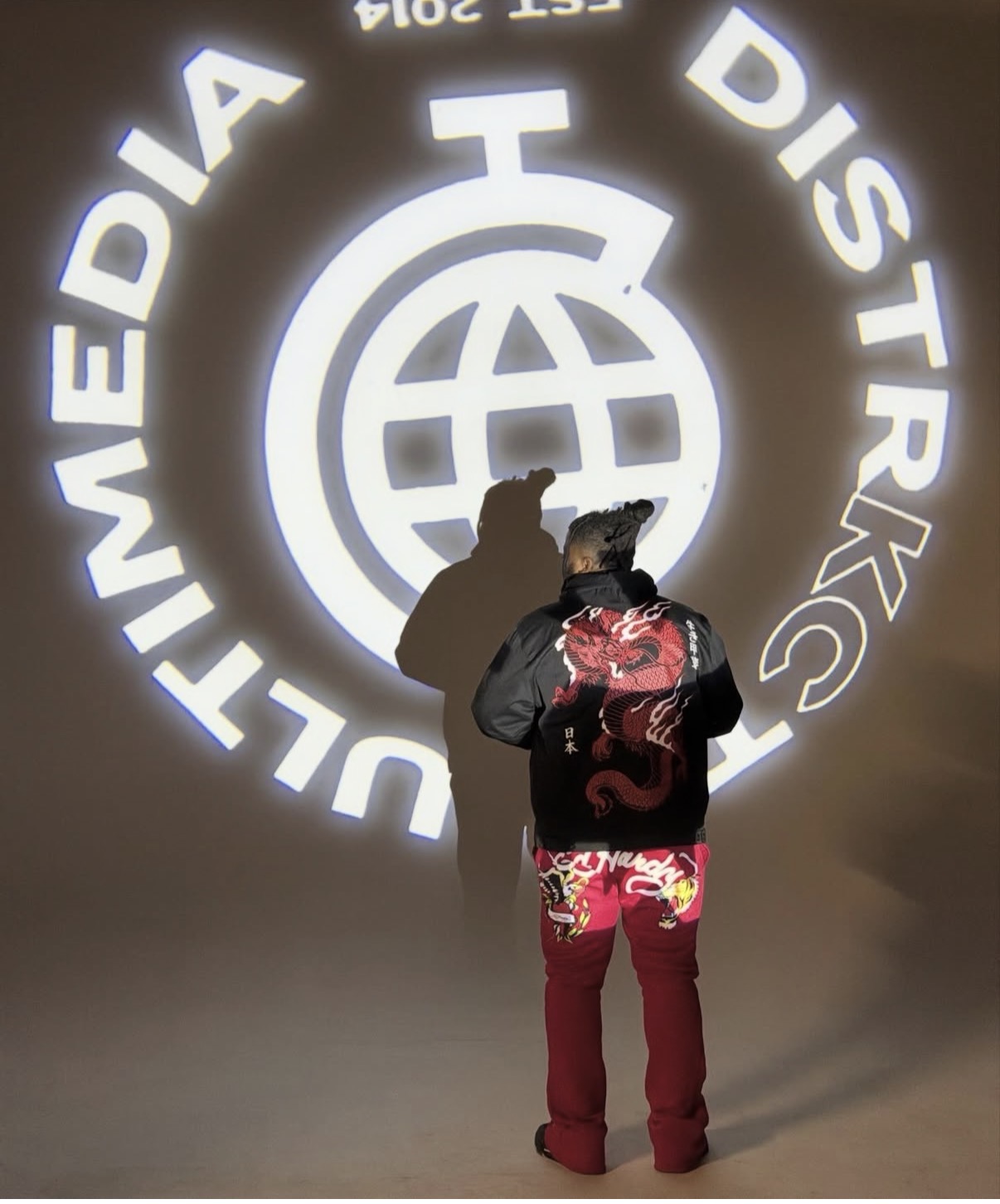 Person with backpack looking at a large illuminated logo of the International Telecommunication Union on a wall.