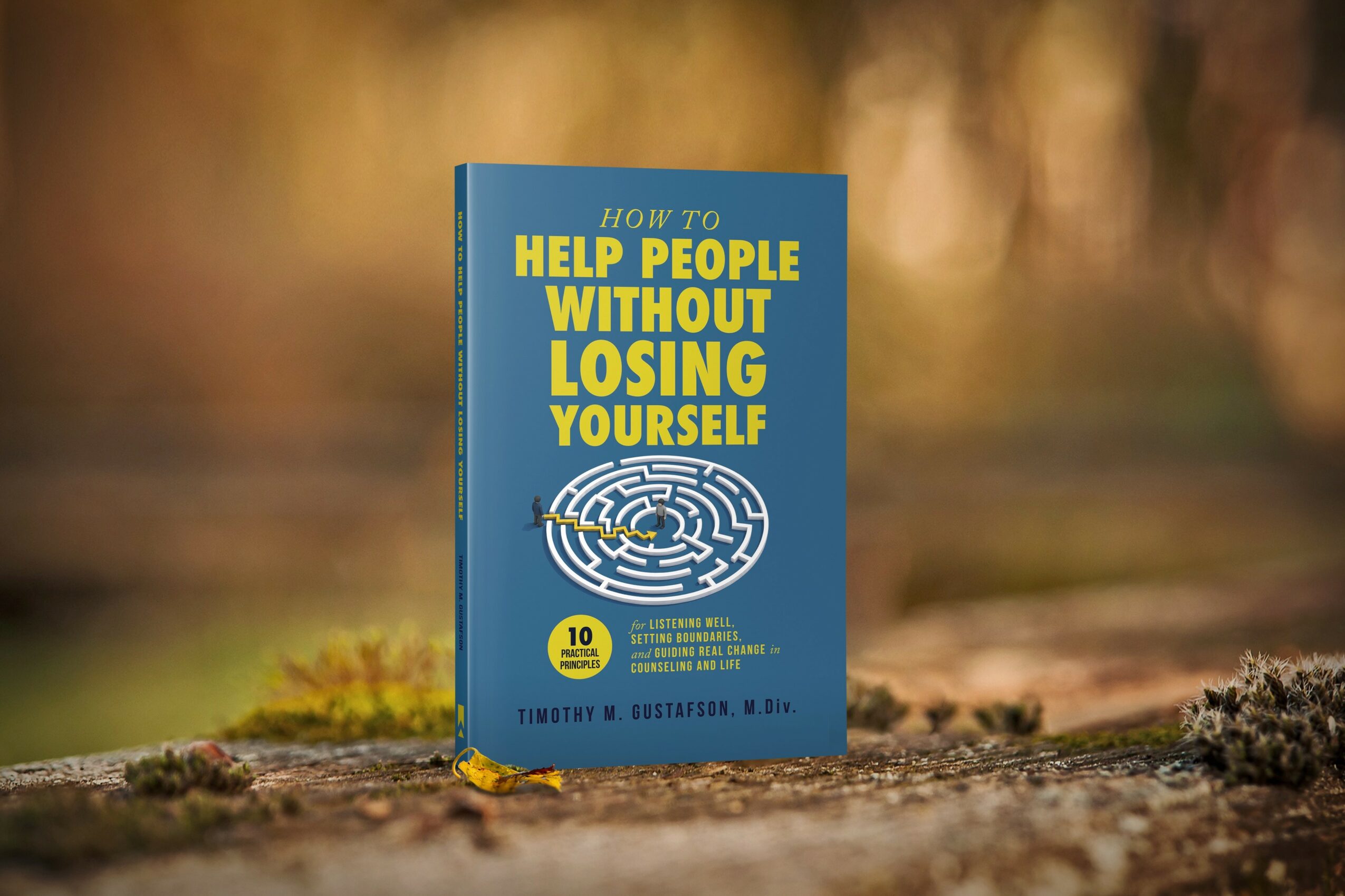 Book titled 'Help People Without Losing Yourself' standing outdoors on a log, with a blurred natural background.