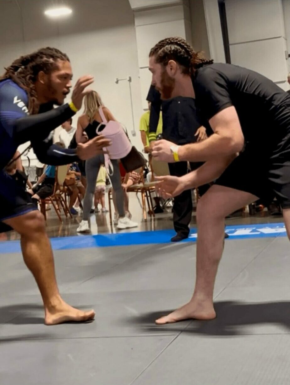 Two people in a fighting stance in a gym, facing each other with gloves, preparing for a match.