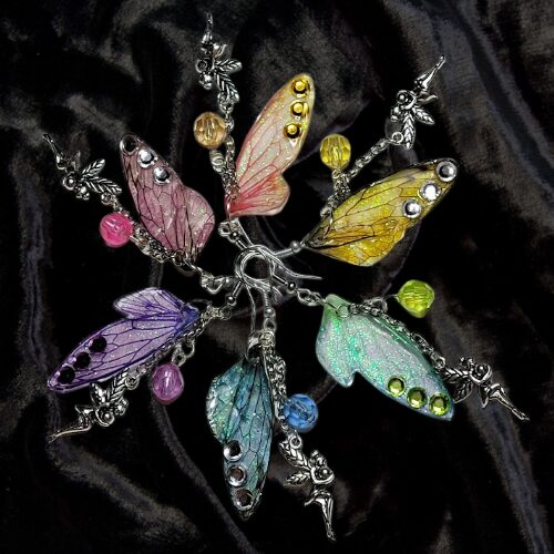 Colorful butterfly-shaped jewelry with beads, arranged in a circular pattern on black fabric.