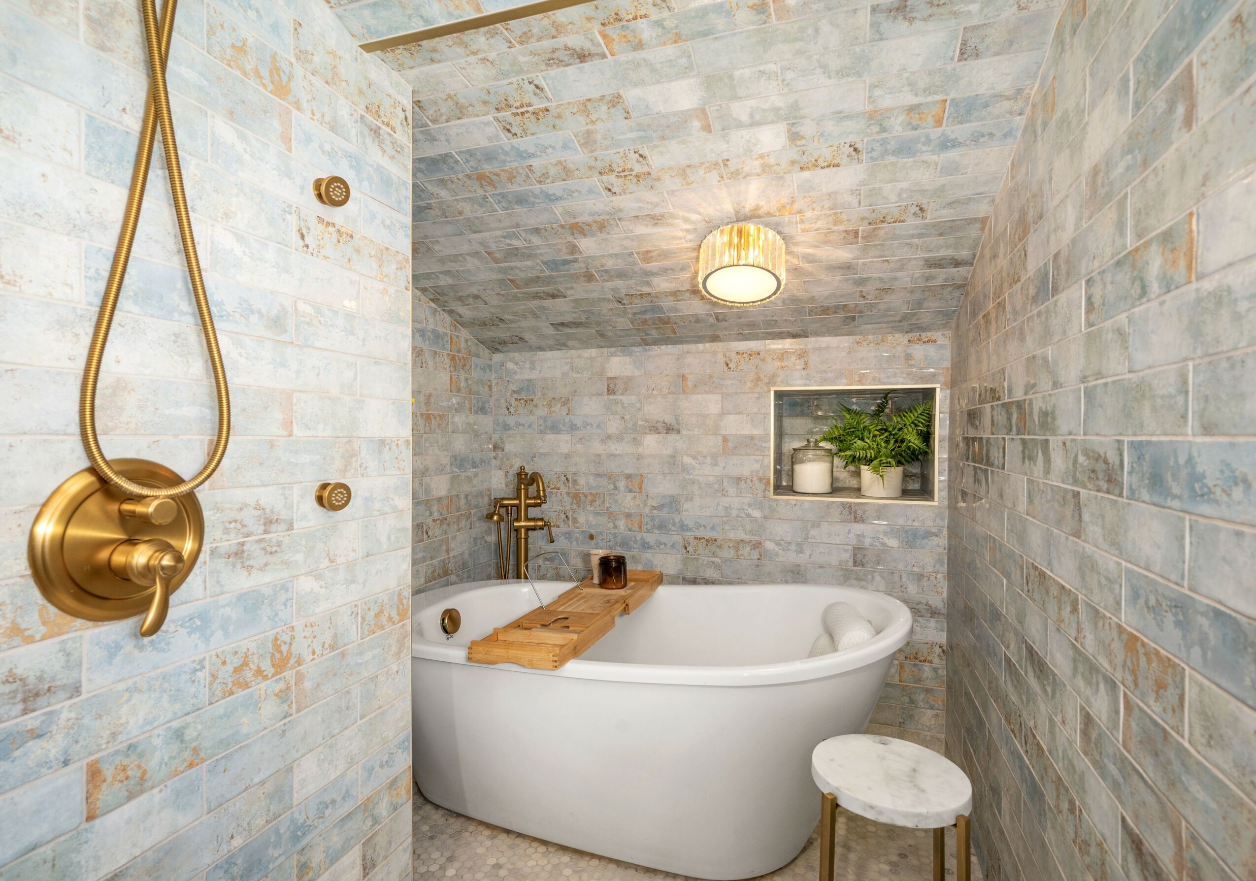 Bathroom with bathtub, wooden tray, small stool, and decorative wall niche with plant.