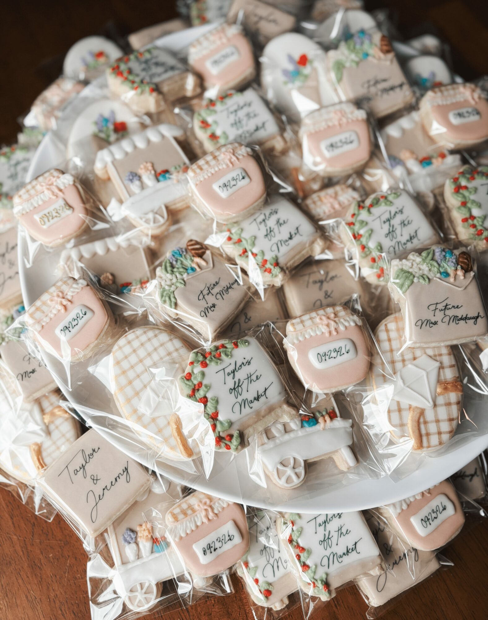 Plate filled with wrapped cookies decorated with holiday-themed paper and labels, some with handwritten messages, on a dark surface.