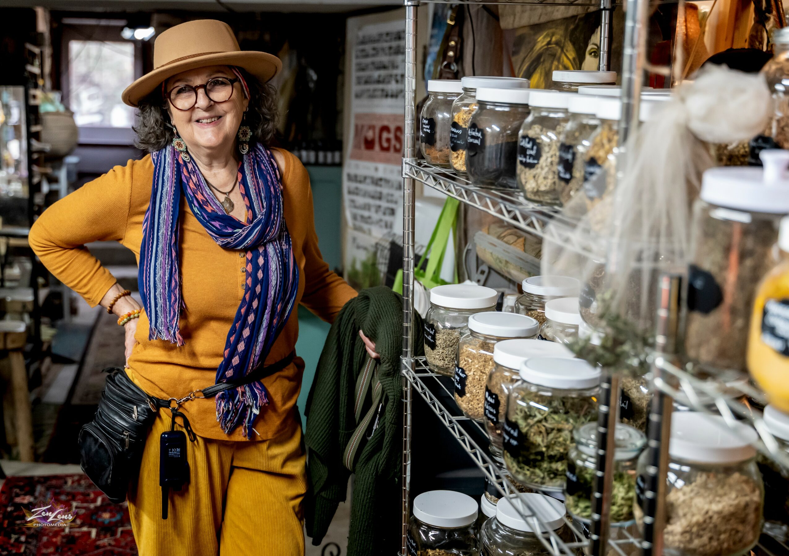 Woman with glasses and hat shopping in a store with shelves of jars and containers.