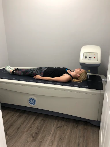 Person lying on a medical scan table with a machine nearby in a clinical room.