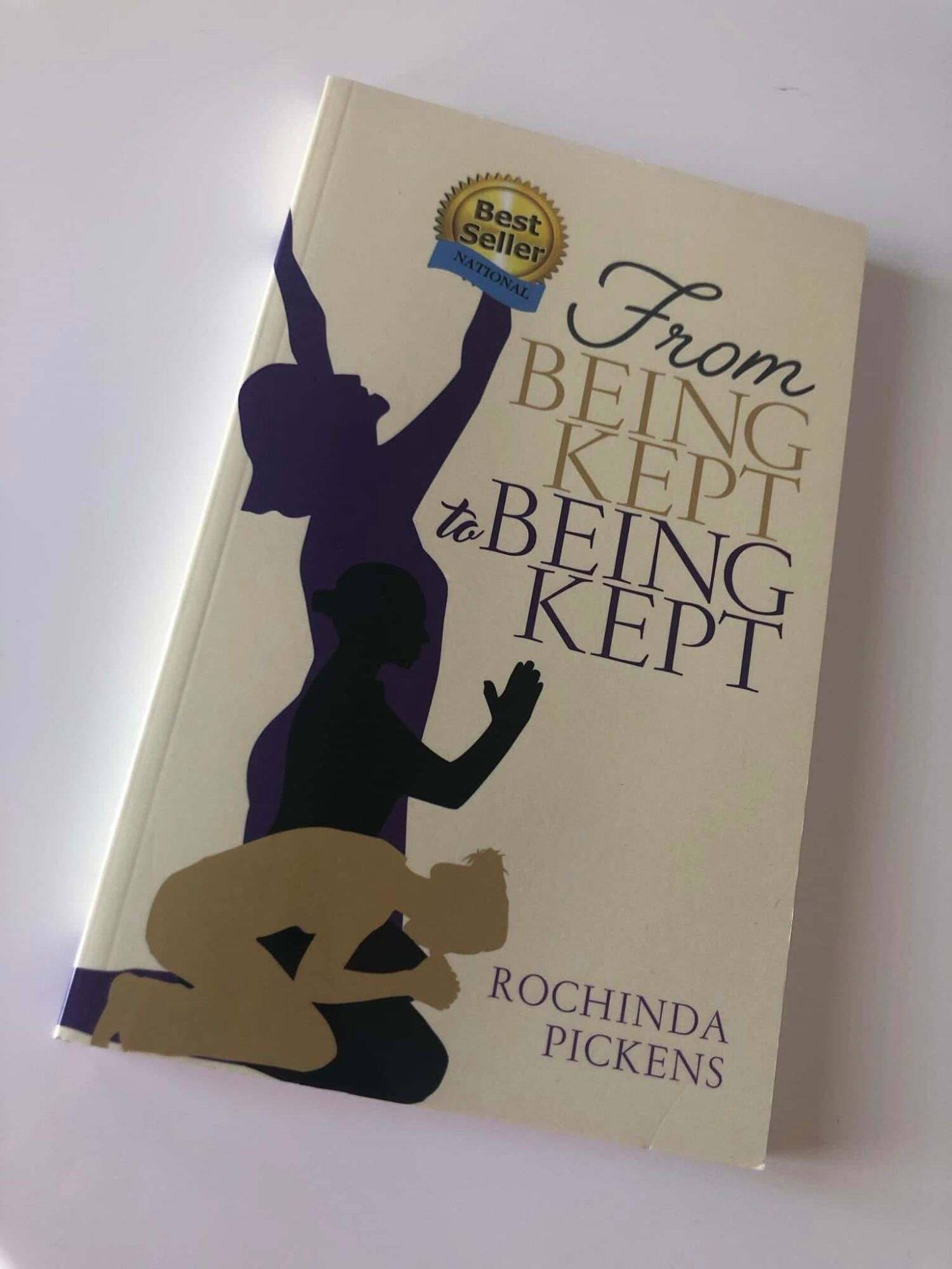 Book cover with silhouettes of two people, one holding a trophy, and text about being kept, by Rochinda Pickens.
