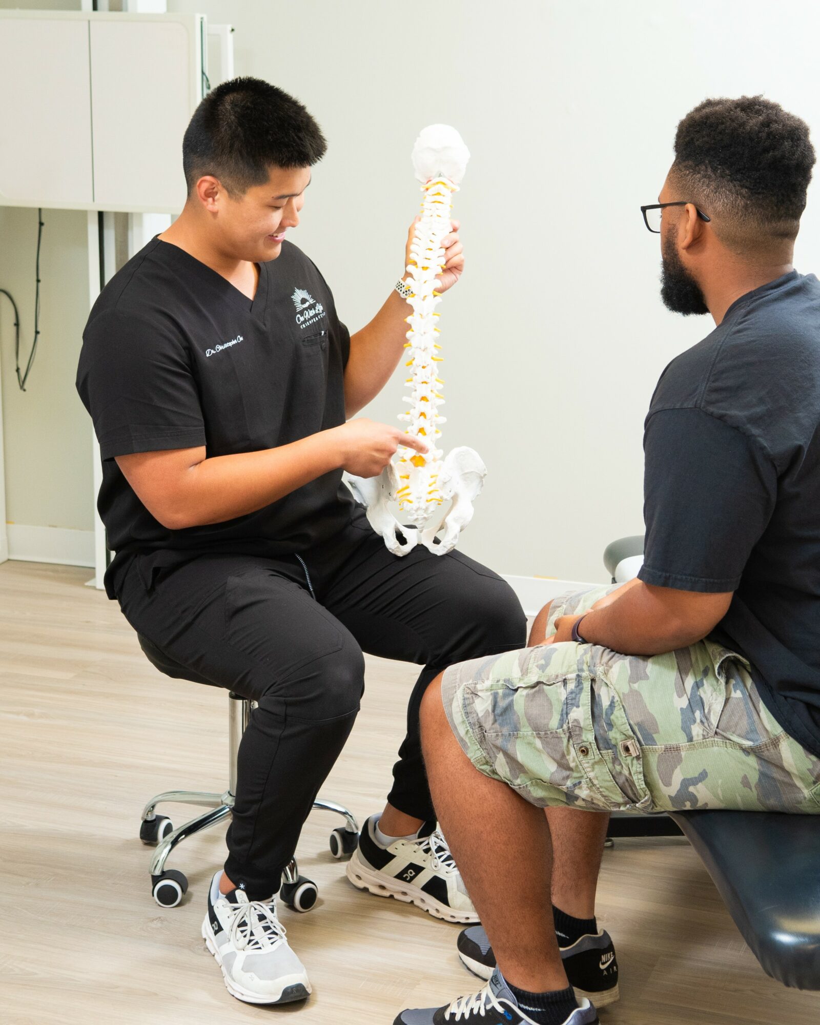 Medical professional shows a spine model to a patient in a clinical setting.