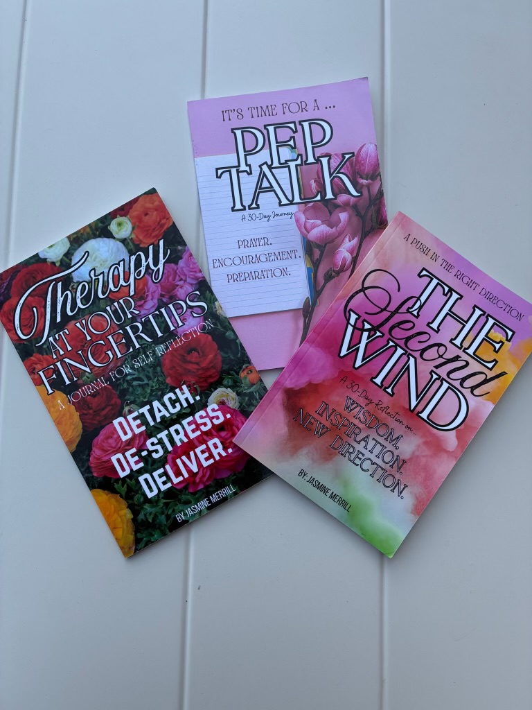 Three books with colorful covers are placed on a white surface, titled 'Therapy for Your Insecurity,' 'It's Time for a Pep Talk,' and 'The Aroma of the Wind.'