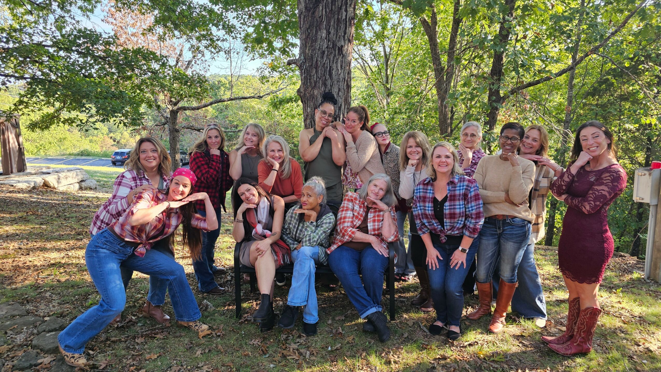 Group of people outdoors in a park, posing for a photo with trees and sunlight in the background.