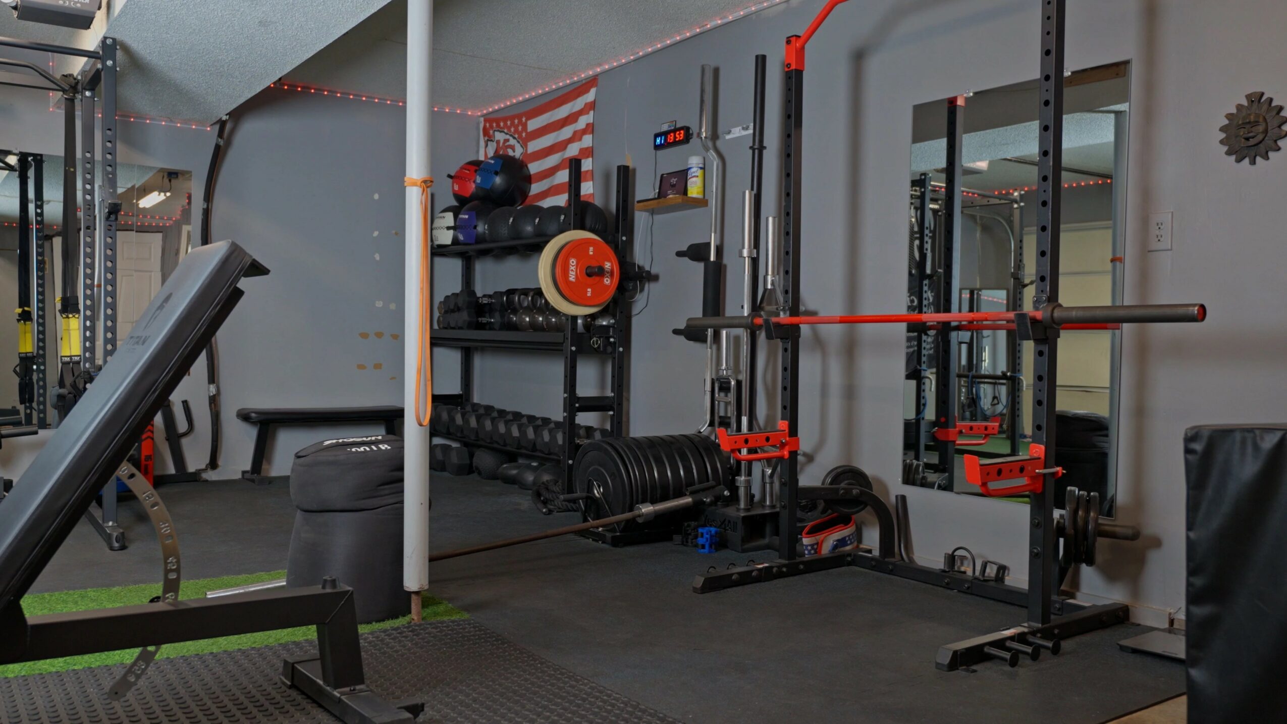 Gym with weightlifting equipment, including a barbell, weight plates, and a mirror on the wall.