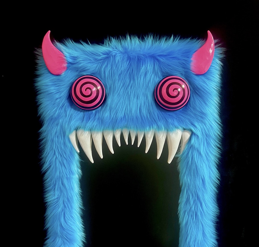Blue furry monster with pink horns, spiral eyes, and sharp teeth, against a black background.