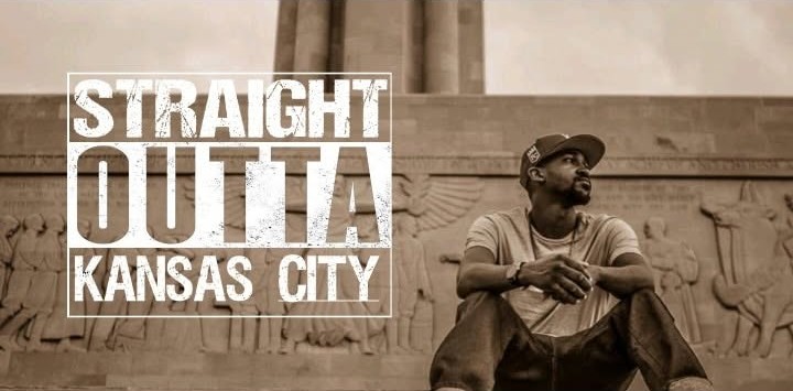 Man sitting against a wall with a mural, wearing a cap and glasses, looking to the side, with text overlay reading 'Straight Outta Kansas City'.