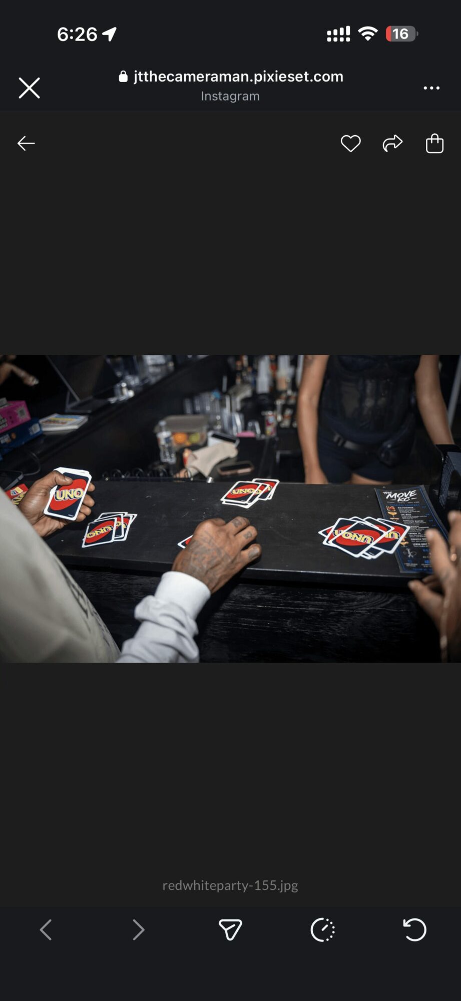 People playing cards at a table with poker chips and drinks, hands visible, in a social setting.