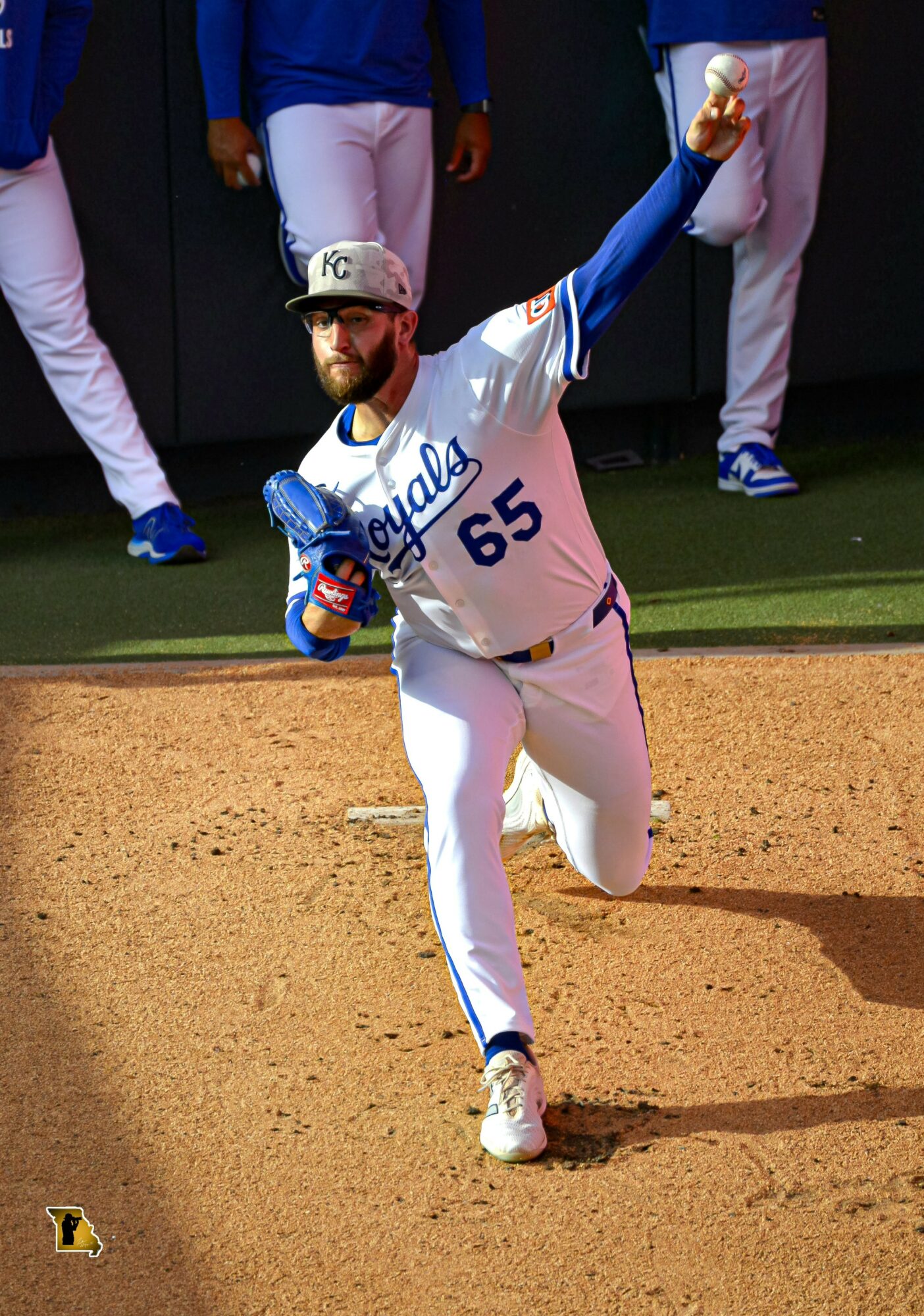 Baseball player in Kansas City Royals uniform running on the field with a bat in hand, celebrating, with teammates in the background.