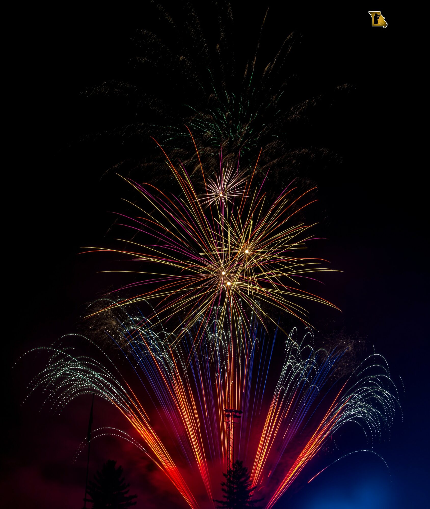 Fireworks explode in the night sky with colorful streaks and bursts, illuminating the darkness with vibrant light.