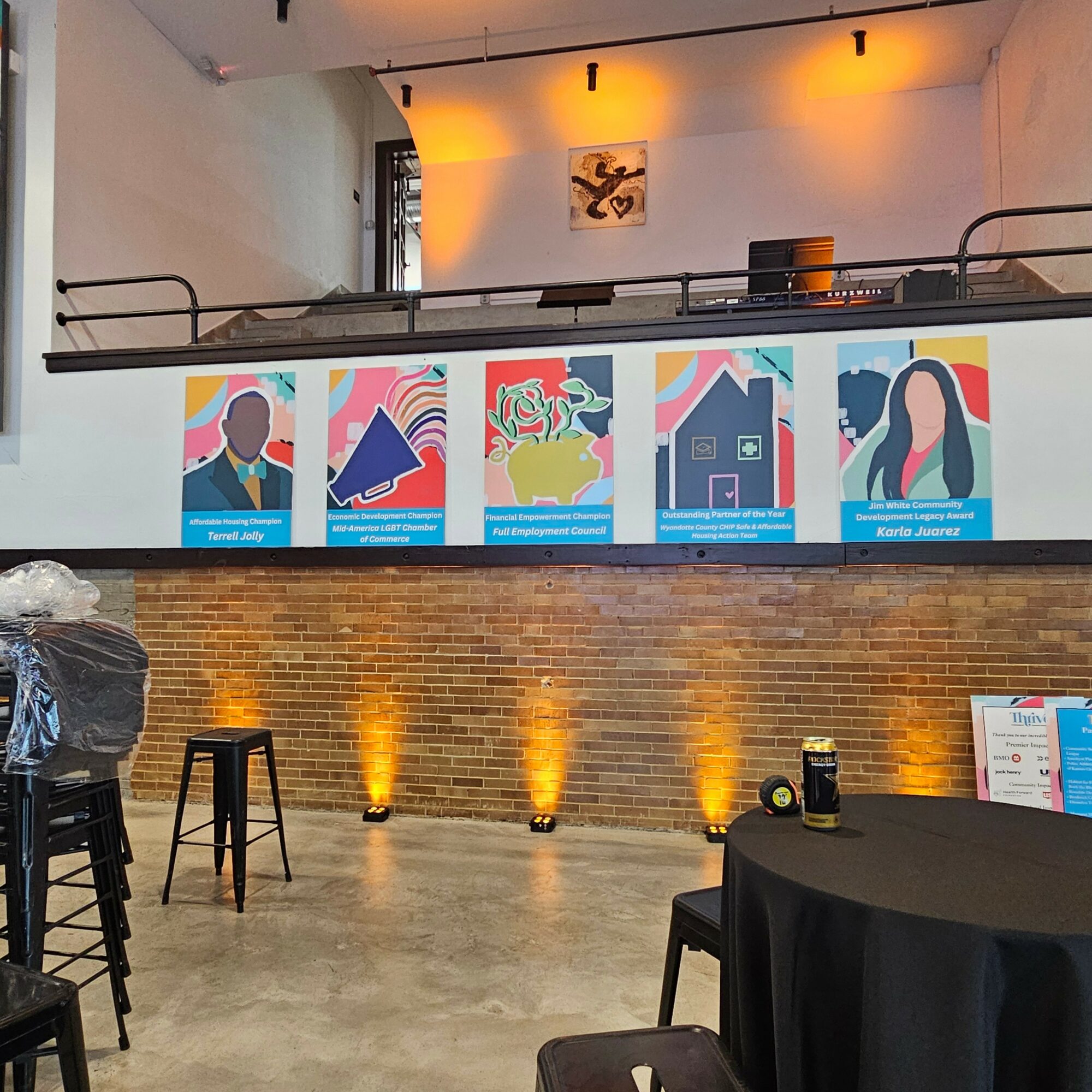 Interior of a modern venue with artwork on the wall, brick wall, and seating area, illuminated by warm lighting.