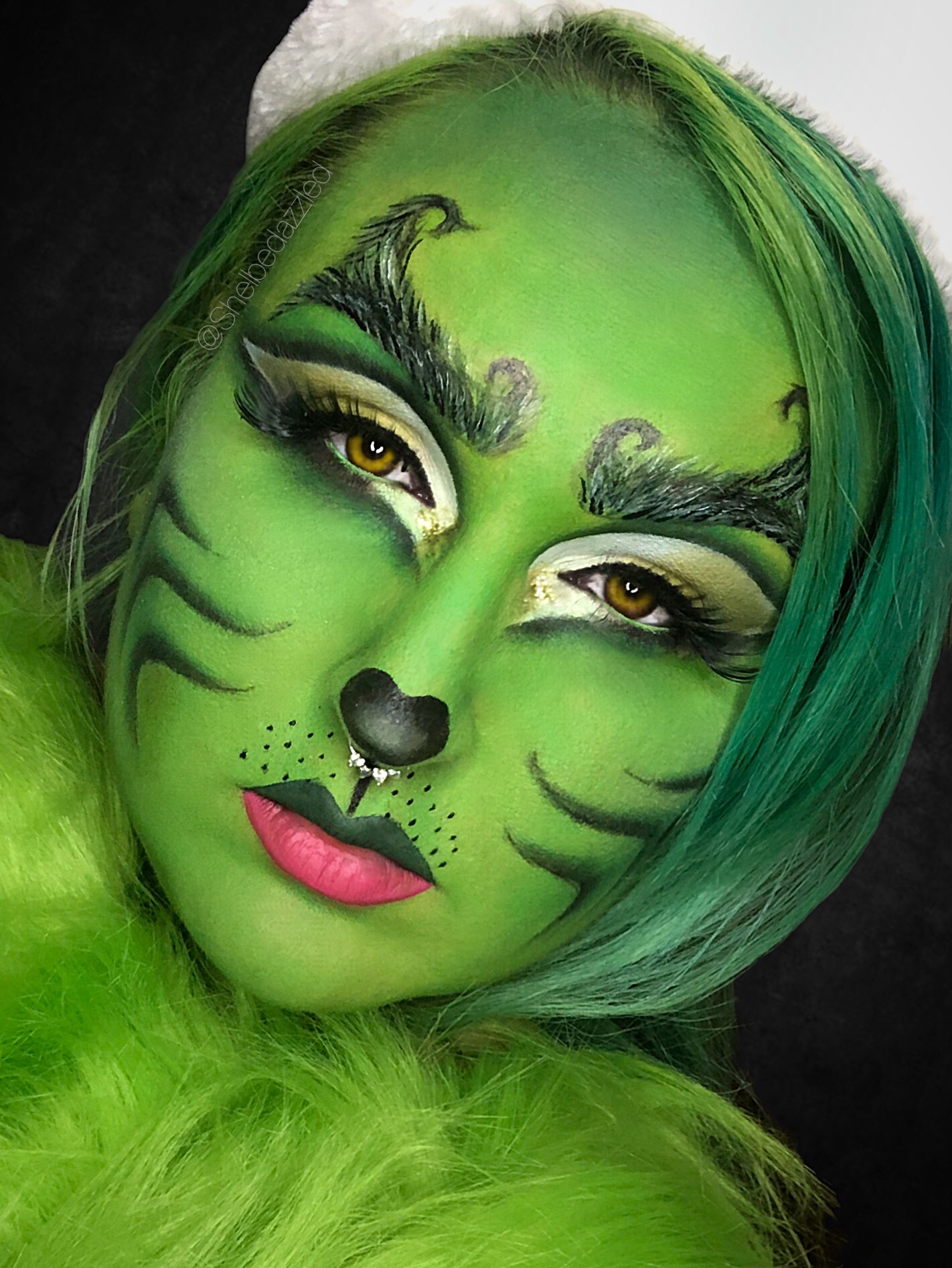 Person with green face paint, tiger-like features, and green hair, looking at the camera with a neutral expression.