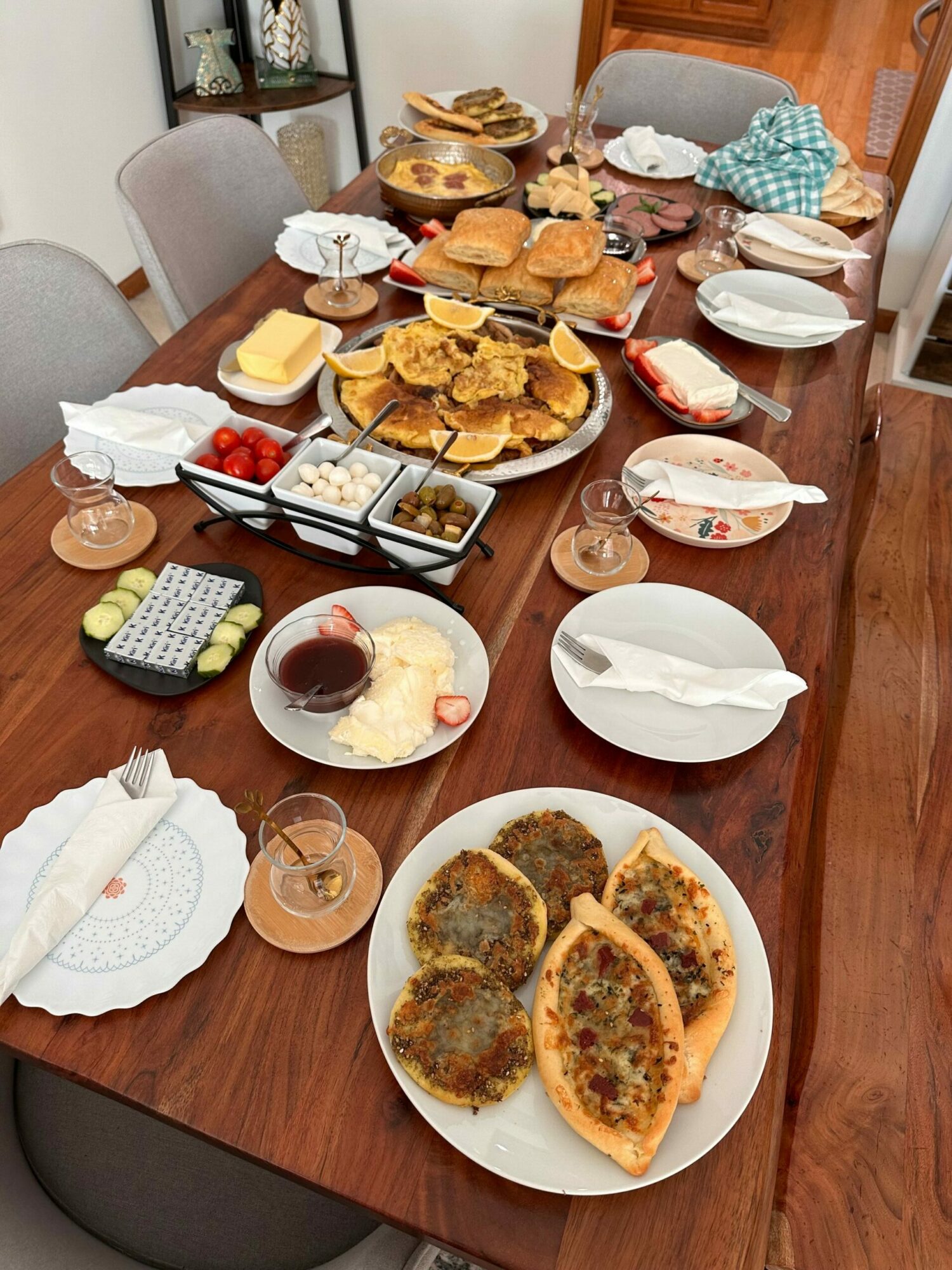 Table with various dishes, drinks, and utensils, including fried food, desserts, and glasses of wine, viewed from the side.