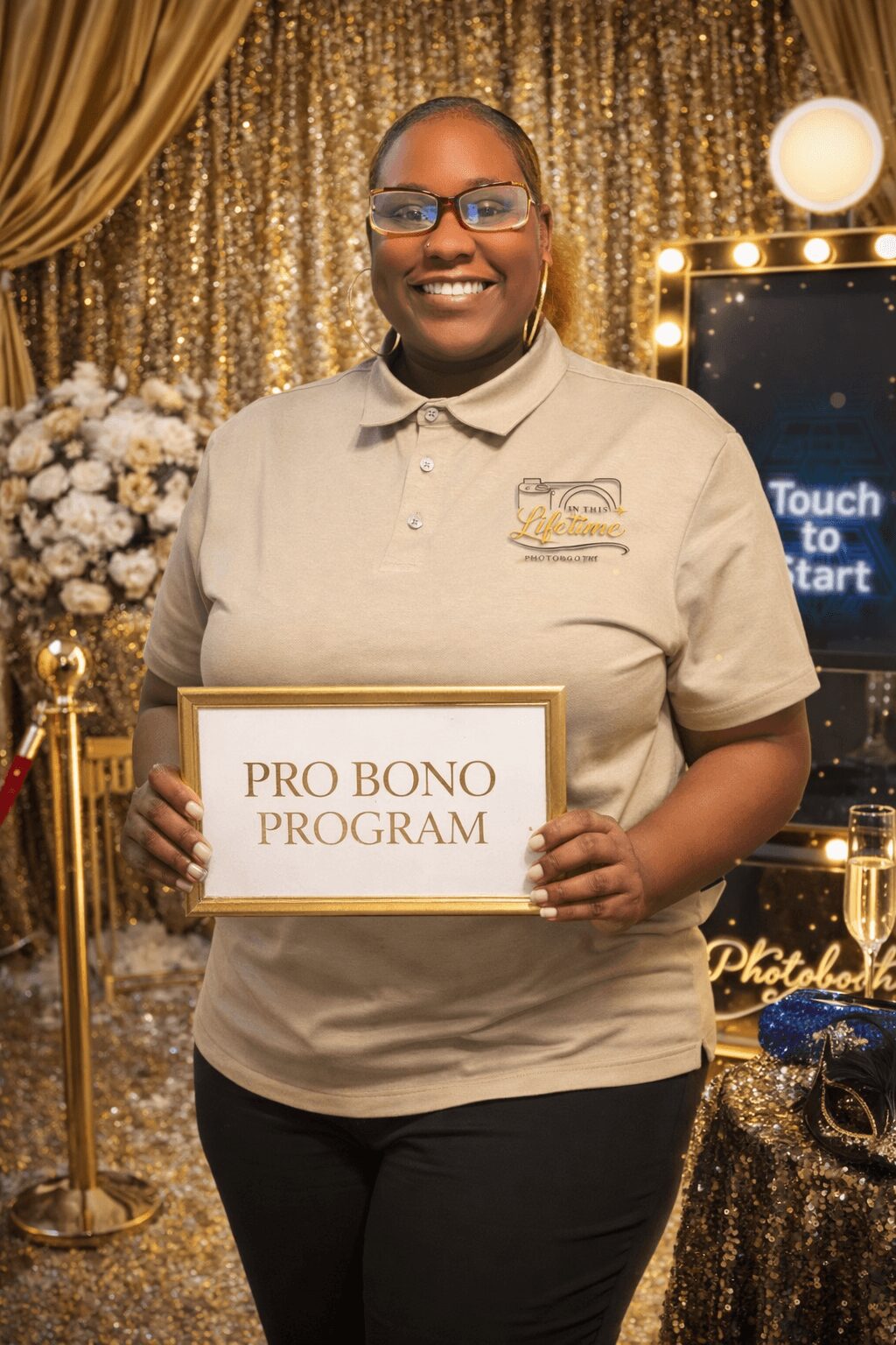 Smiling woman holding a sign that reads 'PRO BONO PROGRAM' in front of a decorated backdrop with flowers and gold curtains.