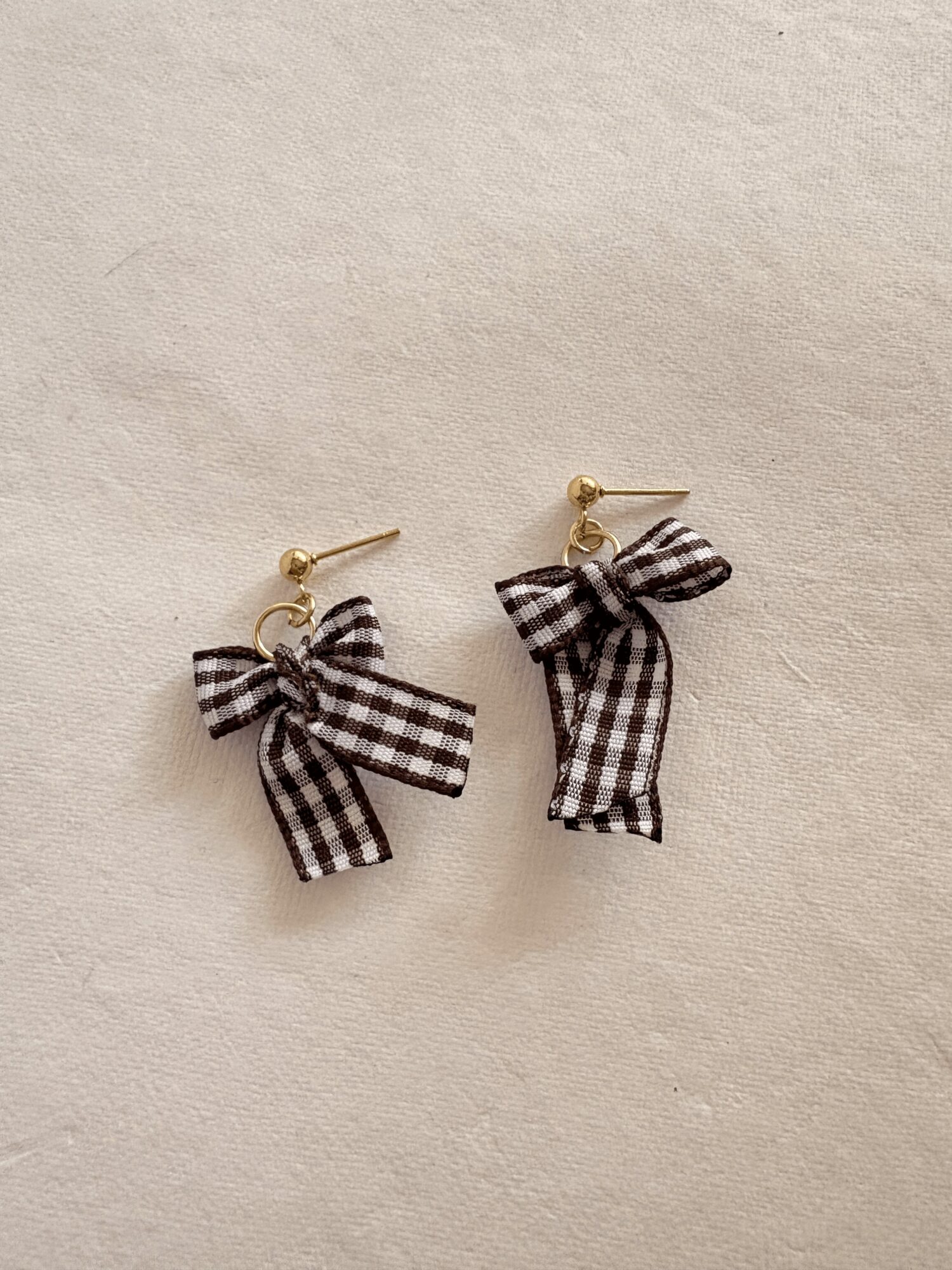 Pair of earrings with black and white checkered bow designs on a light background.