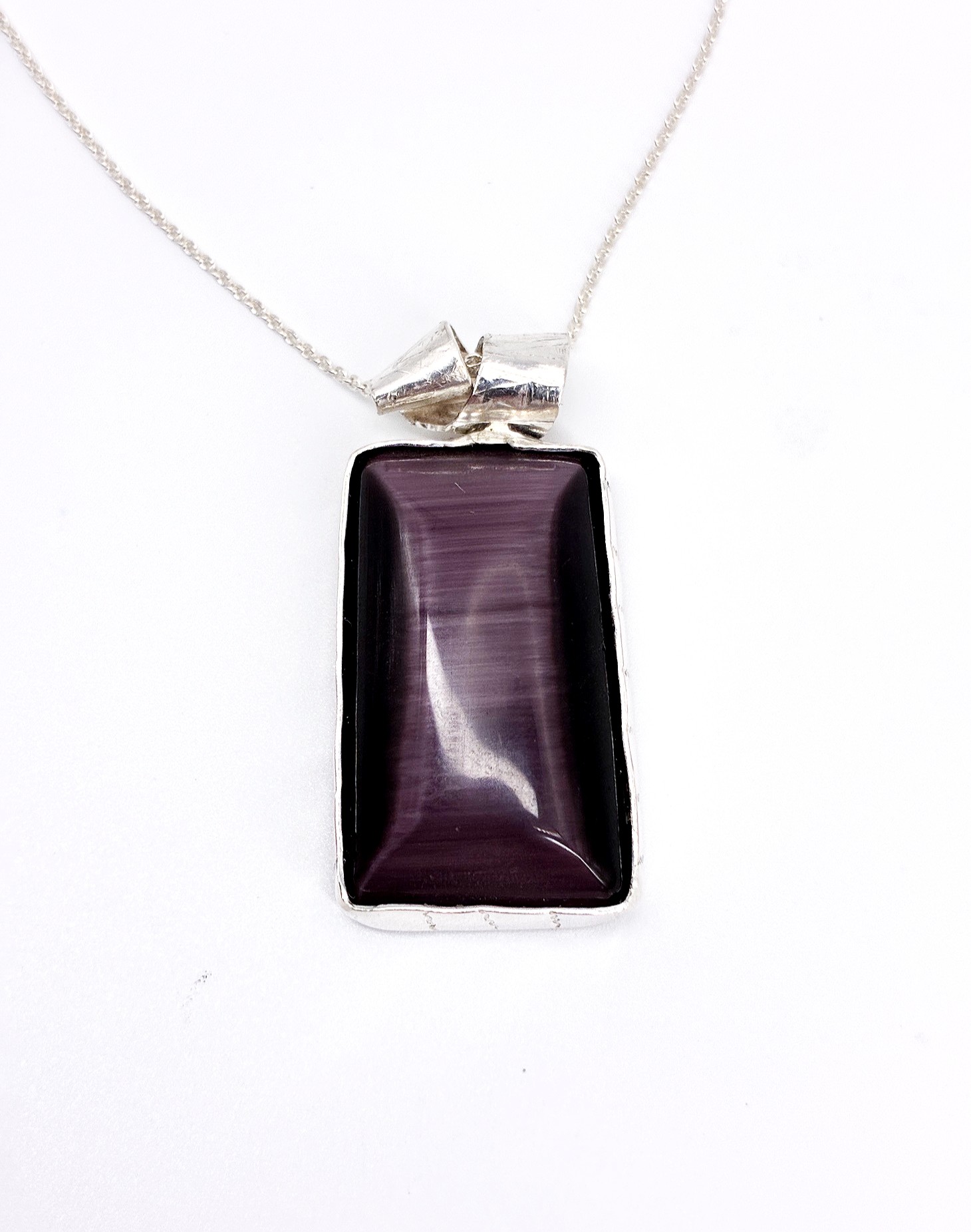 Rectangular purple gemstone pendant on a silver chain, with a silver bail attachment.