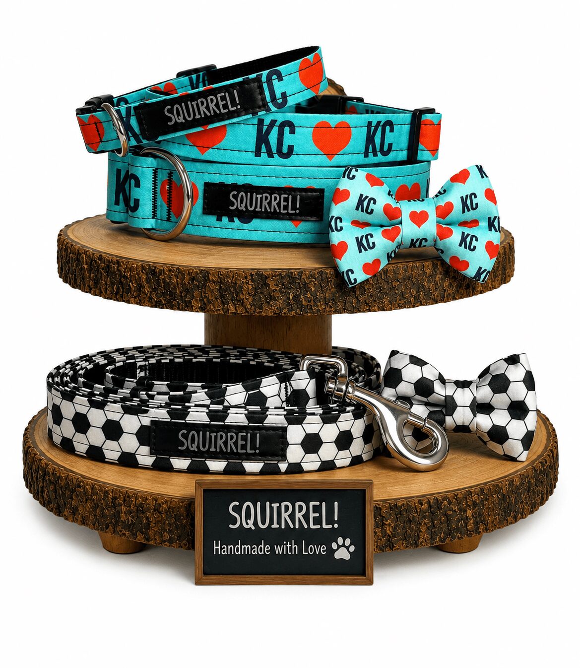 Dog collars and a leash with KC and heart patterns displayed on wooden platforms, with a bow tie and a sign reading 