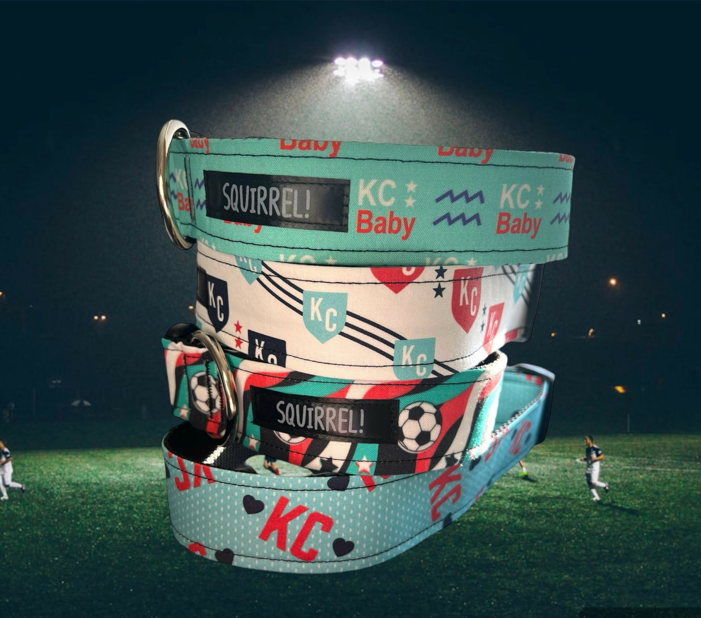 Stack of colorful wristbands with sports and baby themes on a grassy field at night, stadium lights in background.