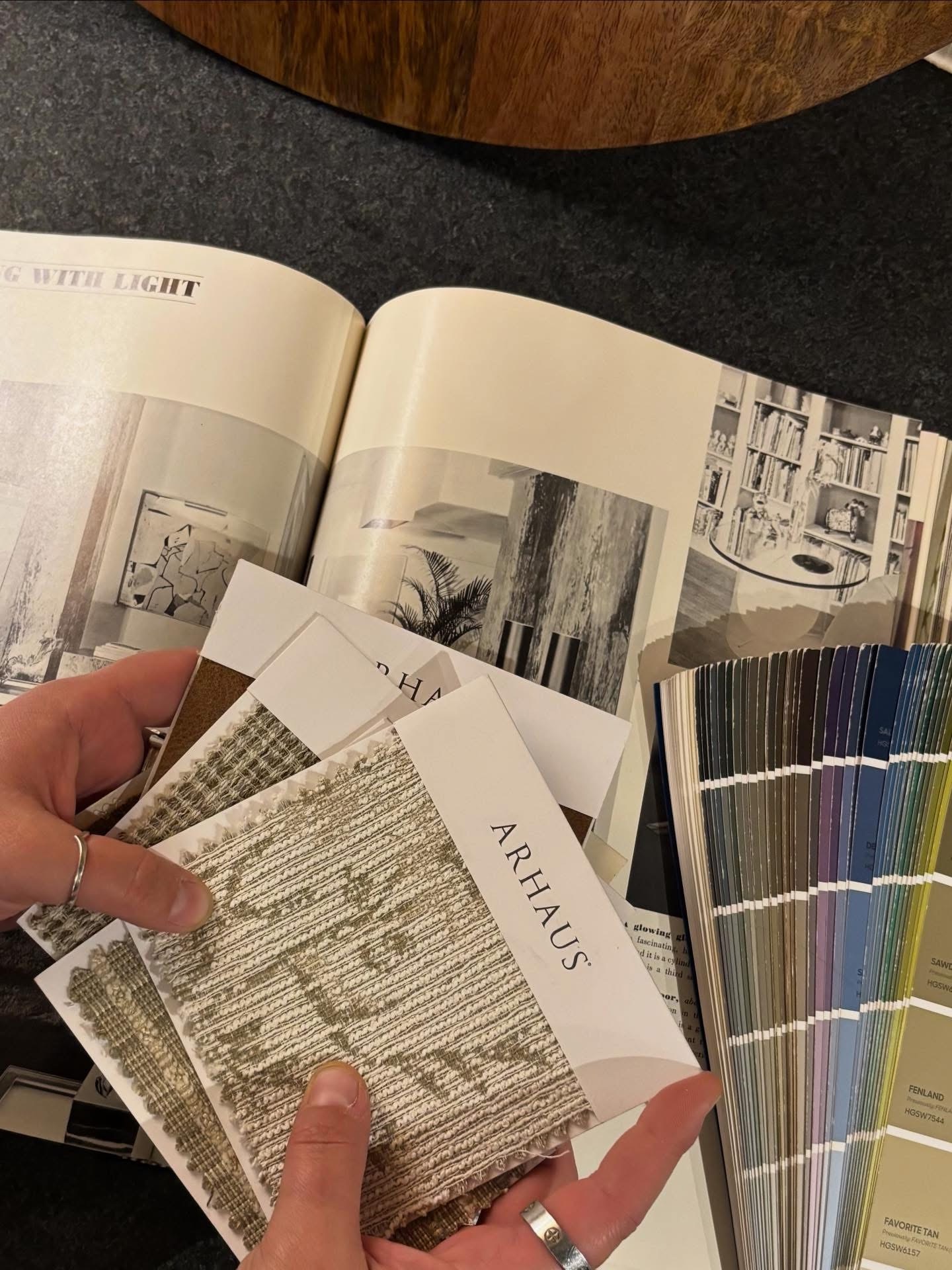 Open book with black and white images, color swatches, and a hand holding fabric samples labeled 'ARTHAUS'.