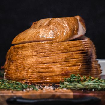 Stacked slices of a layered cake with a piece on top, garnished with herbs on a wooden surface.