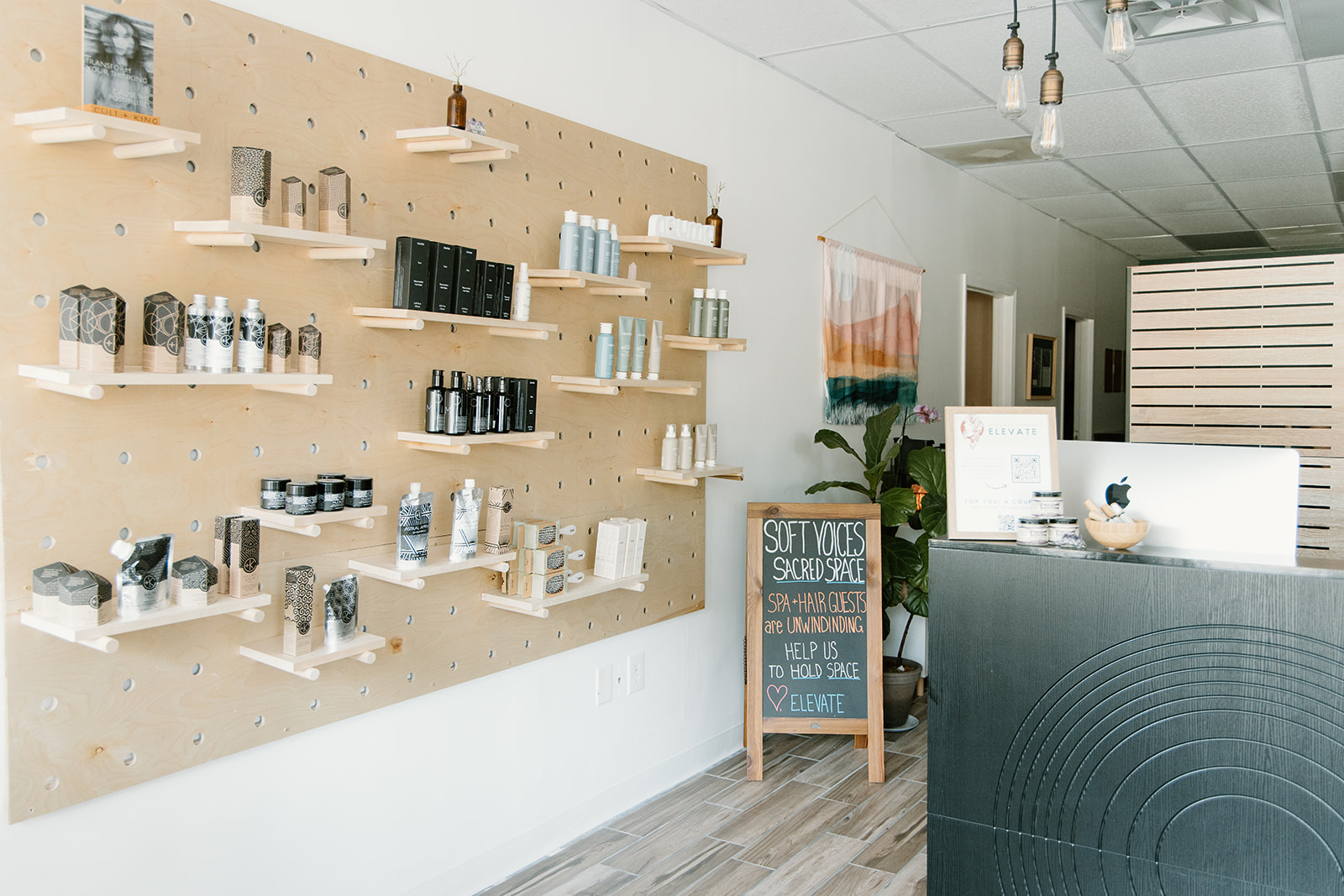 Display of skincare products on a beige pegboard wall in a store, with a reception desk and promotional sign nearby.