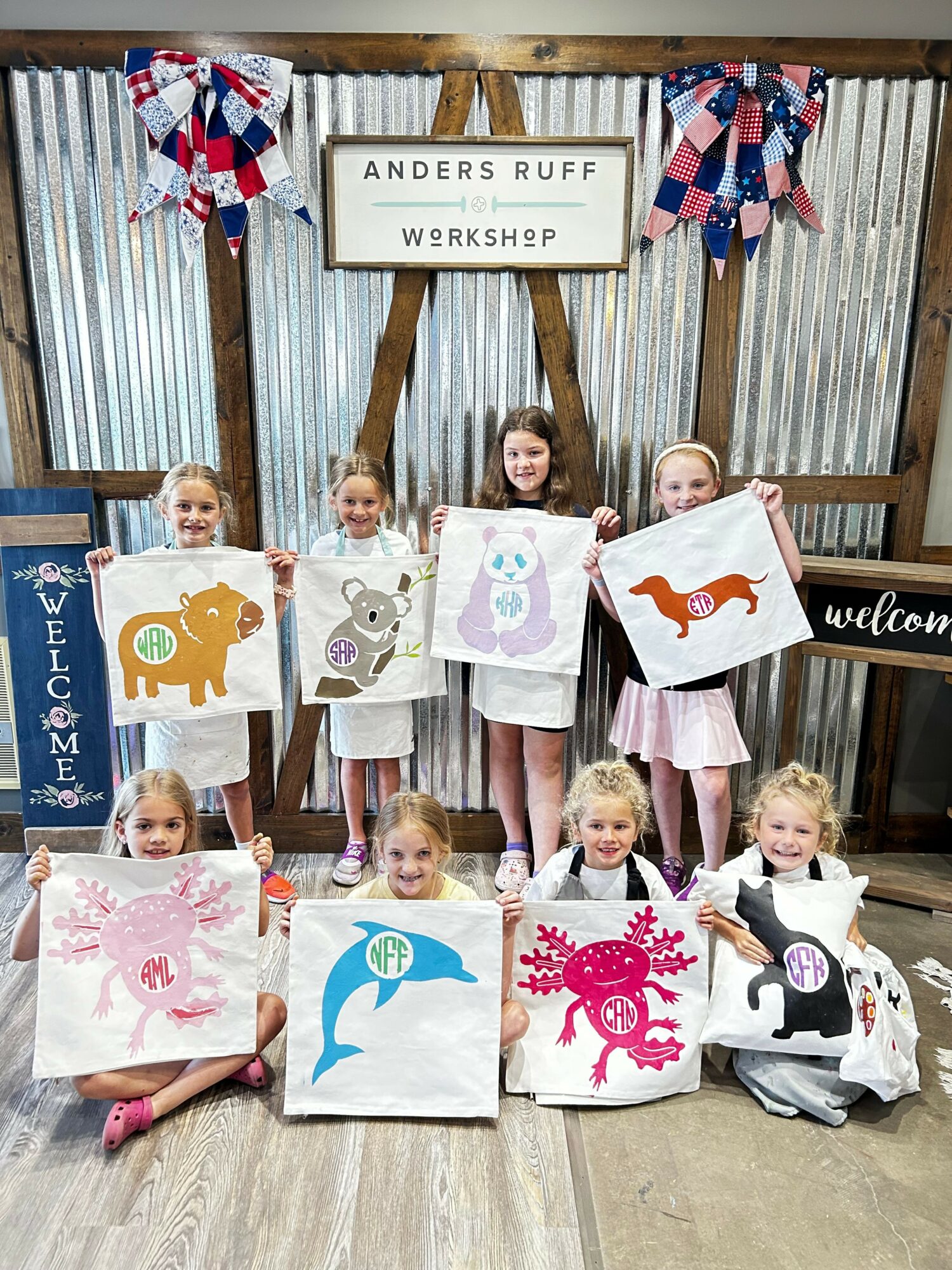 Children holding decorated boxes and bags in a workshop setting with a sign reading 'Anders RUFF Workshop'.